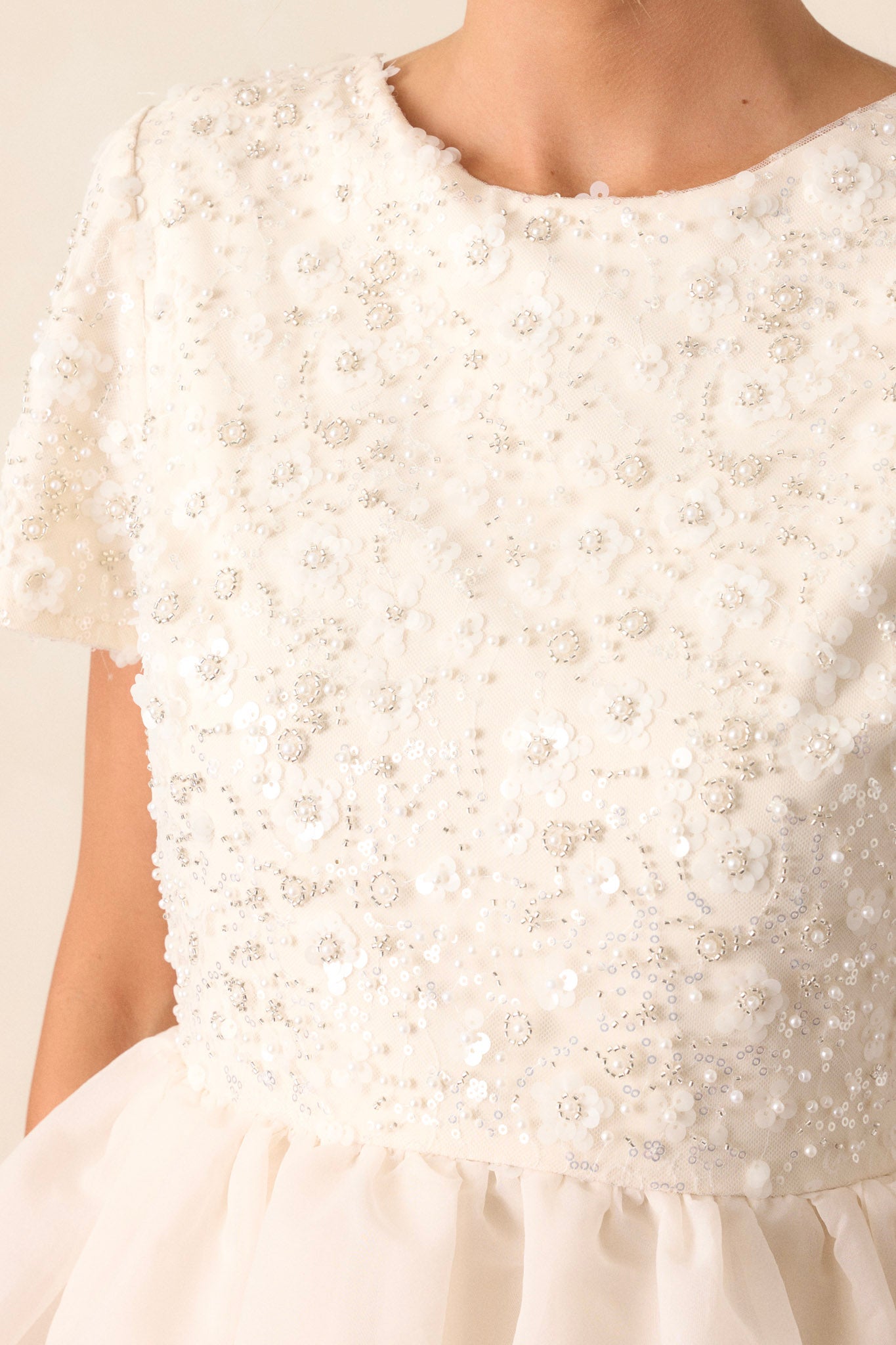 Close-up of the dreamlike dress focusing on the pearls embellishing the top and the delicate tulle tiers.