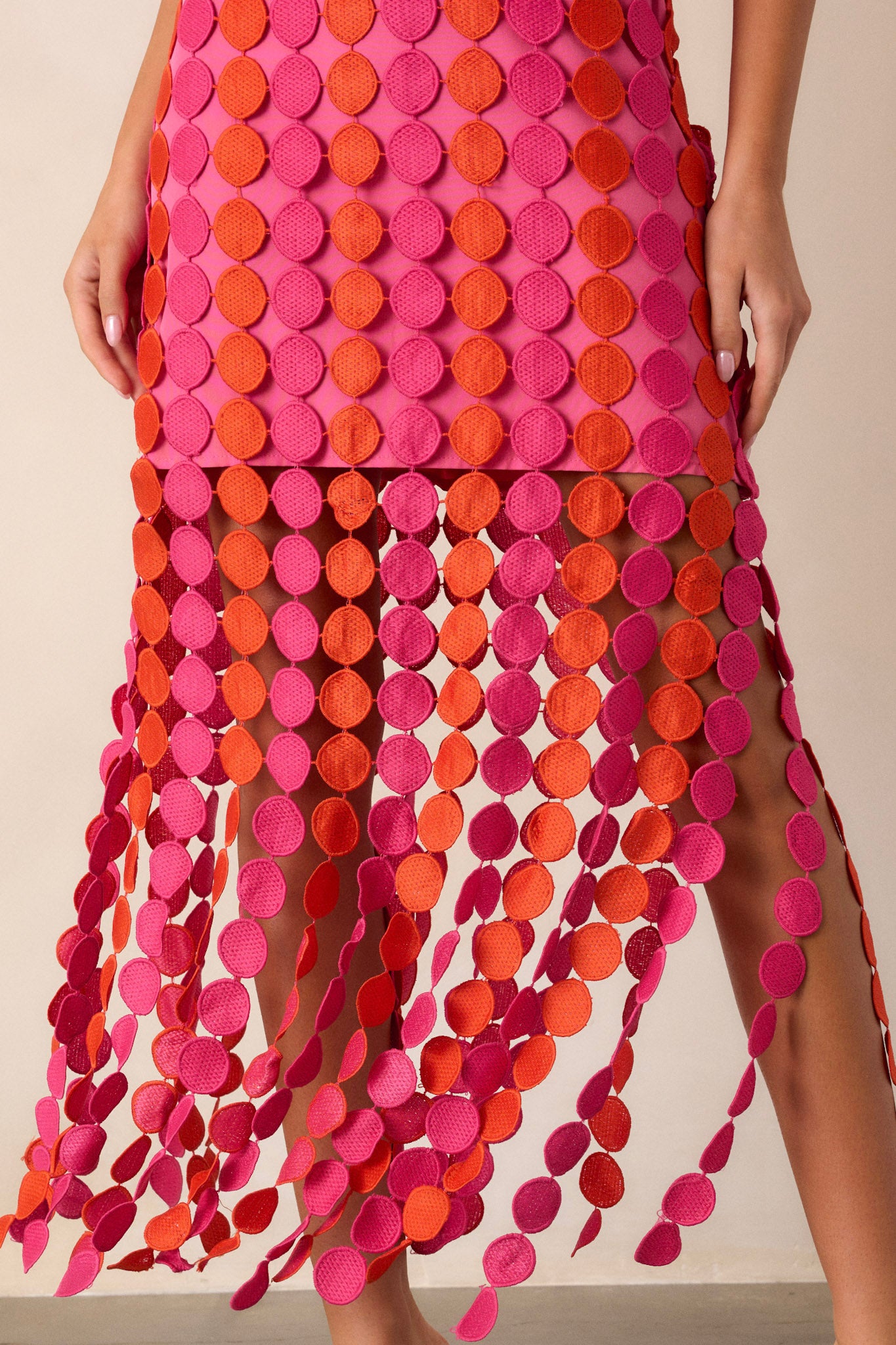 Close-up of the bottom of this pink dress focusing on the pink and orange fringe detailing