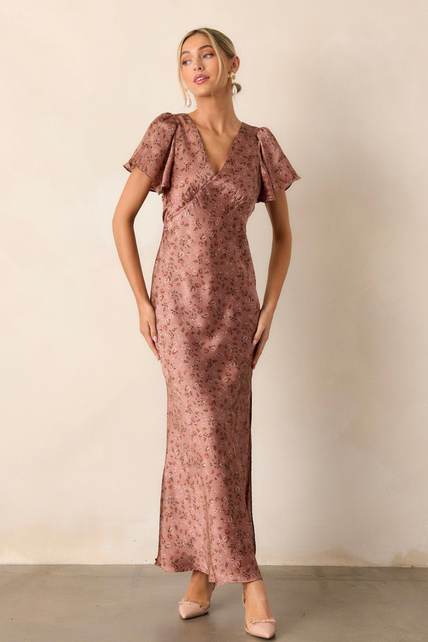 Front angled view of the dusty rose dress featuring a plunging v-neckline, flutter sleeves, a functional back zipper, and a high leg slit