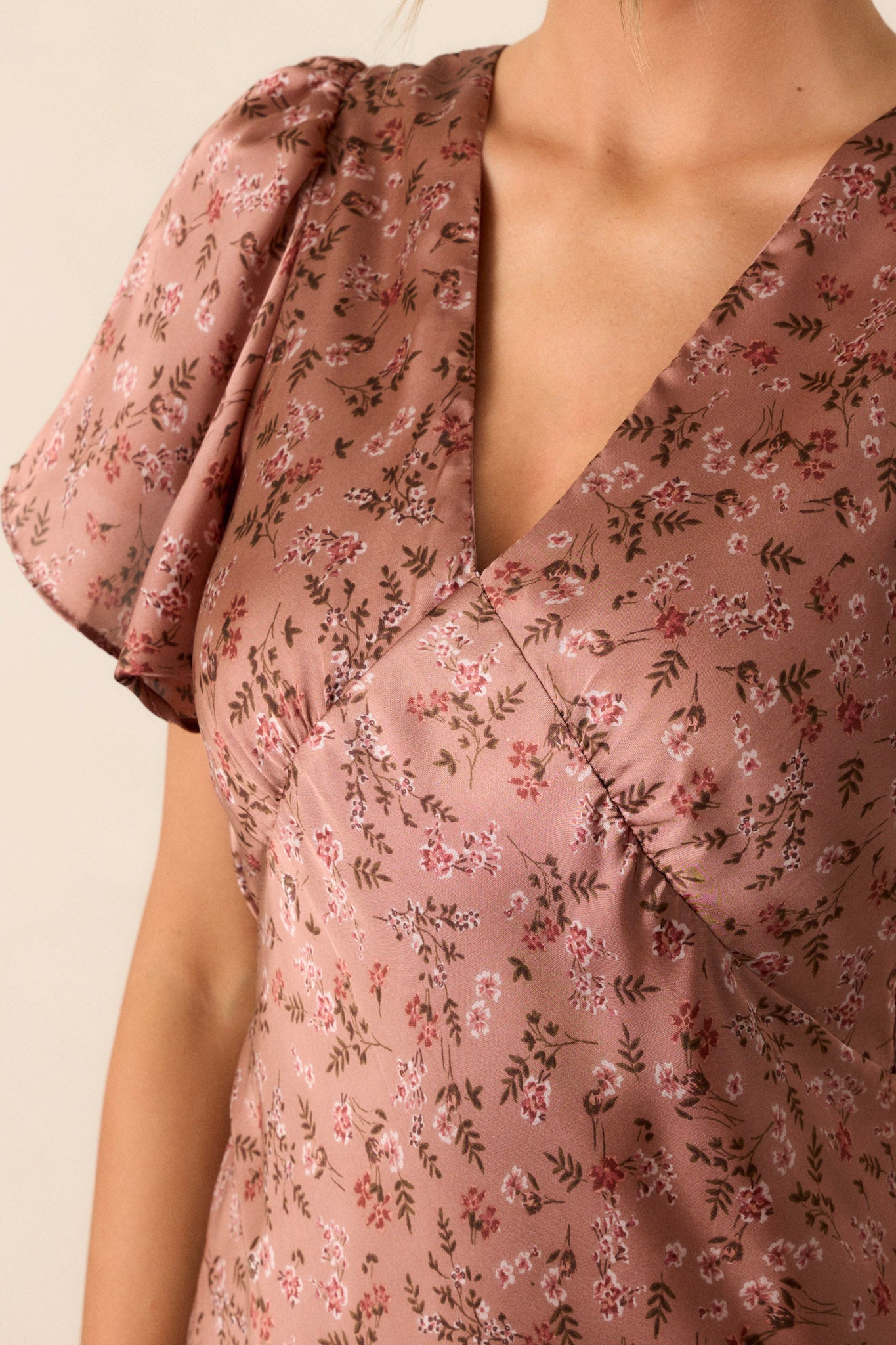 Close-up of the dusty rose dress focusing on the plunging v-neckline, the delicate flutter sleeves, and the texture of the fabric near the back zipper