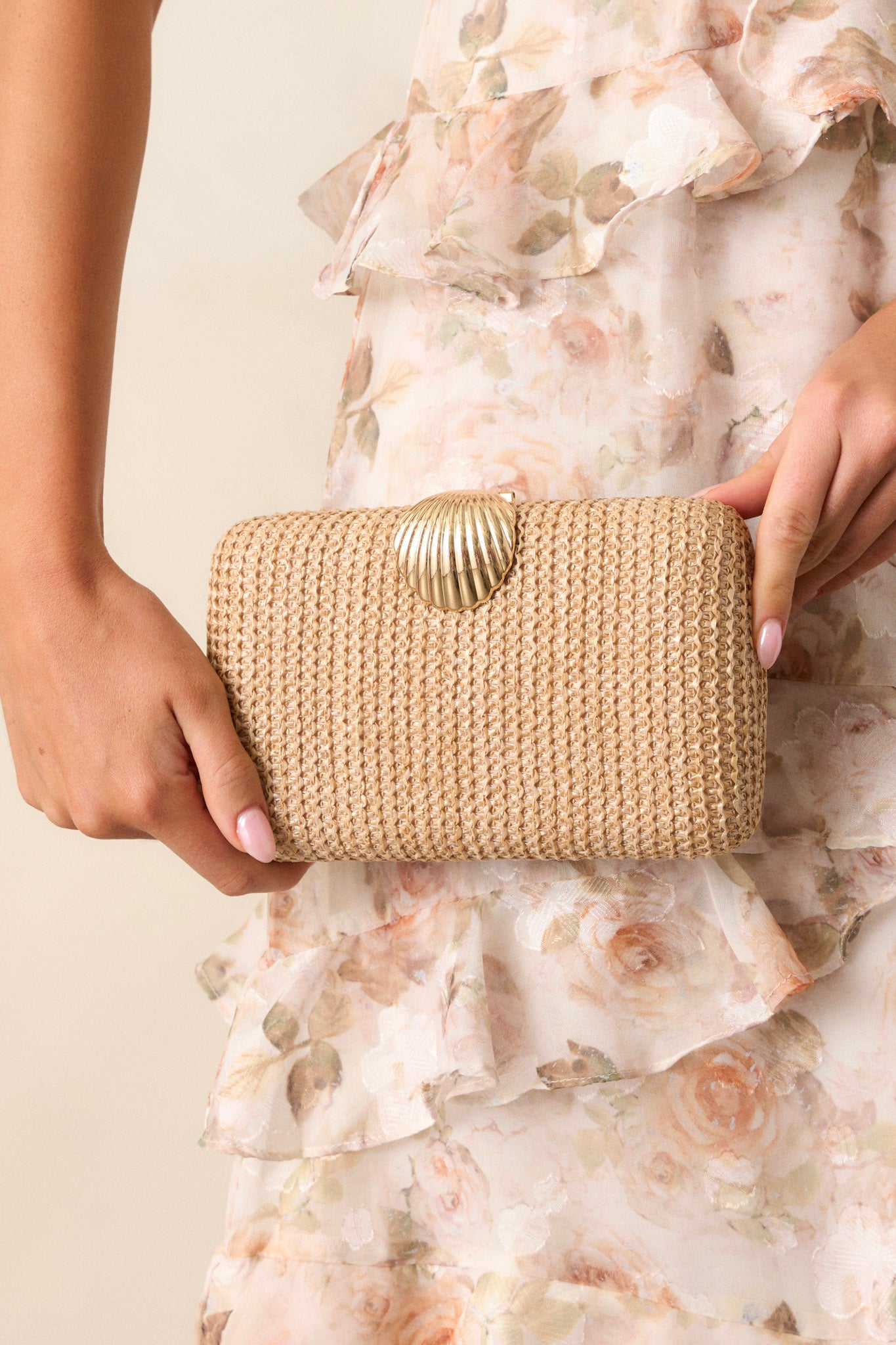 This beige woven clutch features a gold seashell snap closure, two hidden gold clasps for the optional chain, a gold chain and an open interior.