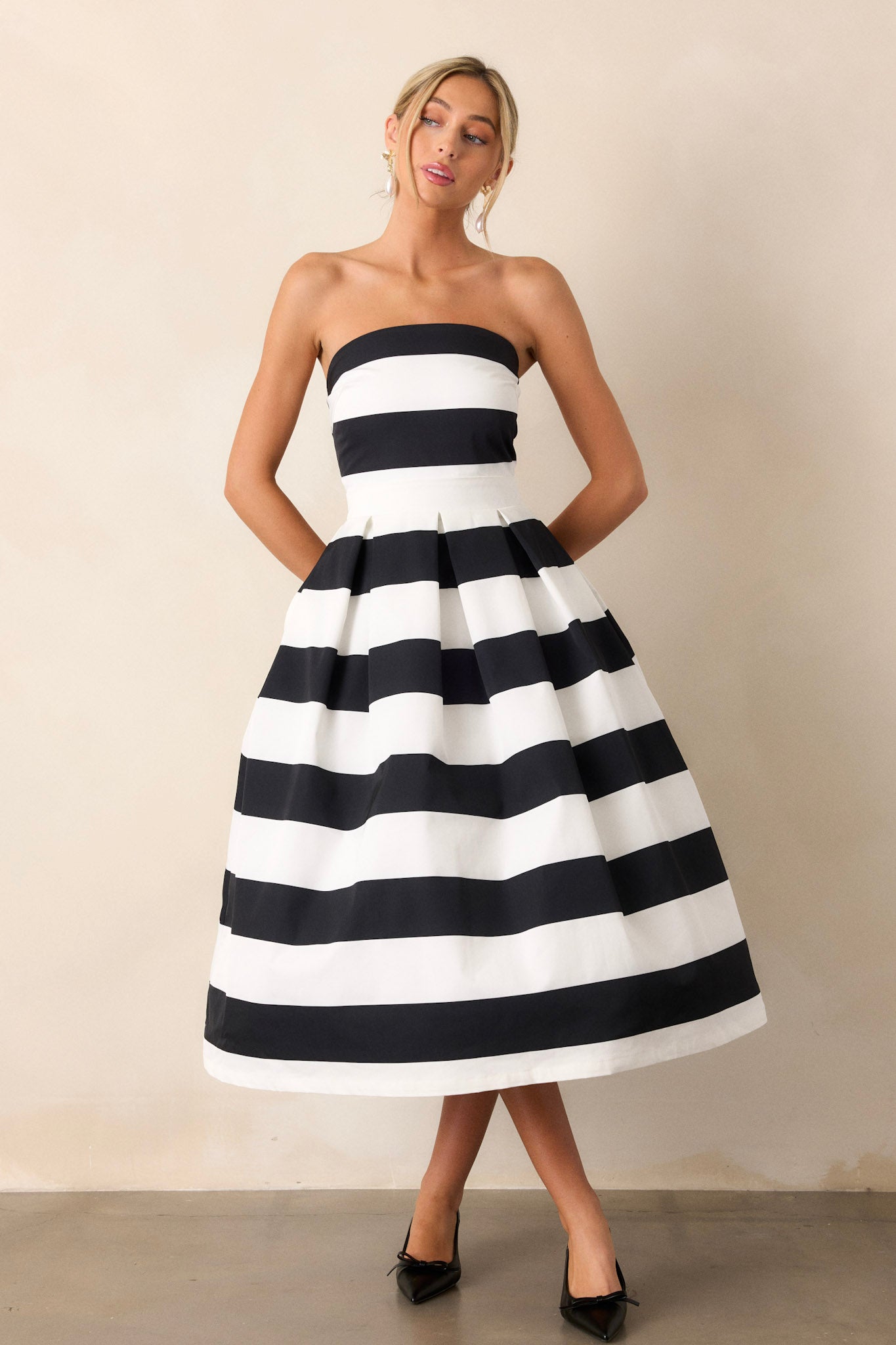 This dress features a strapless neckline, a discrete zipper down the back, a thick waistband, functional hip pockets, and a timeless stripe pattern.