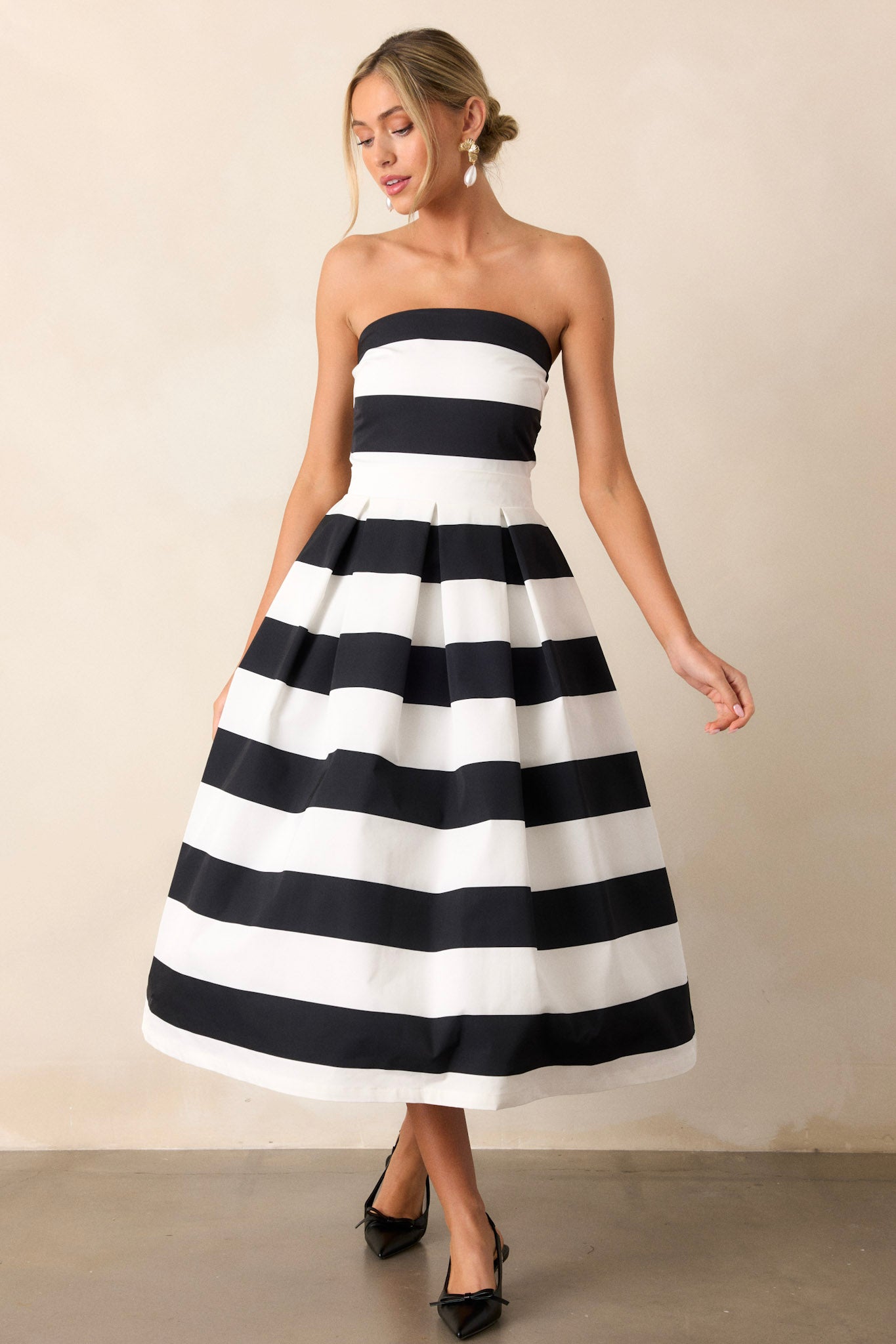 Front angled view of the dress featuring a strapless neckline, thick waistband, functional hip pockets, and a timeless stripe pattern,