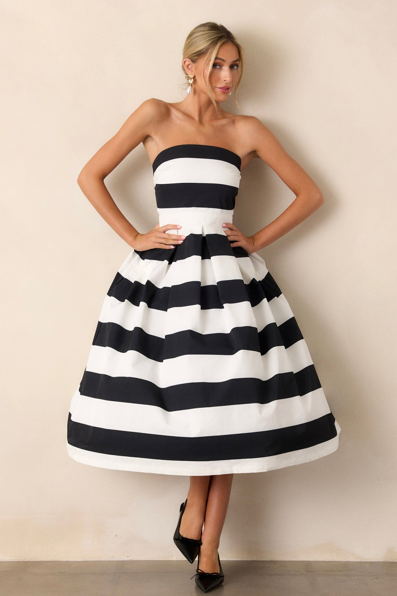 Front view of a dress featuring a strapless neckline, a thick waistband, functional hip pockets, and a timeless stripe pattern.