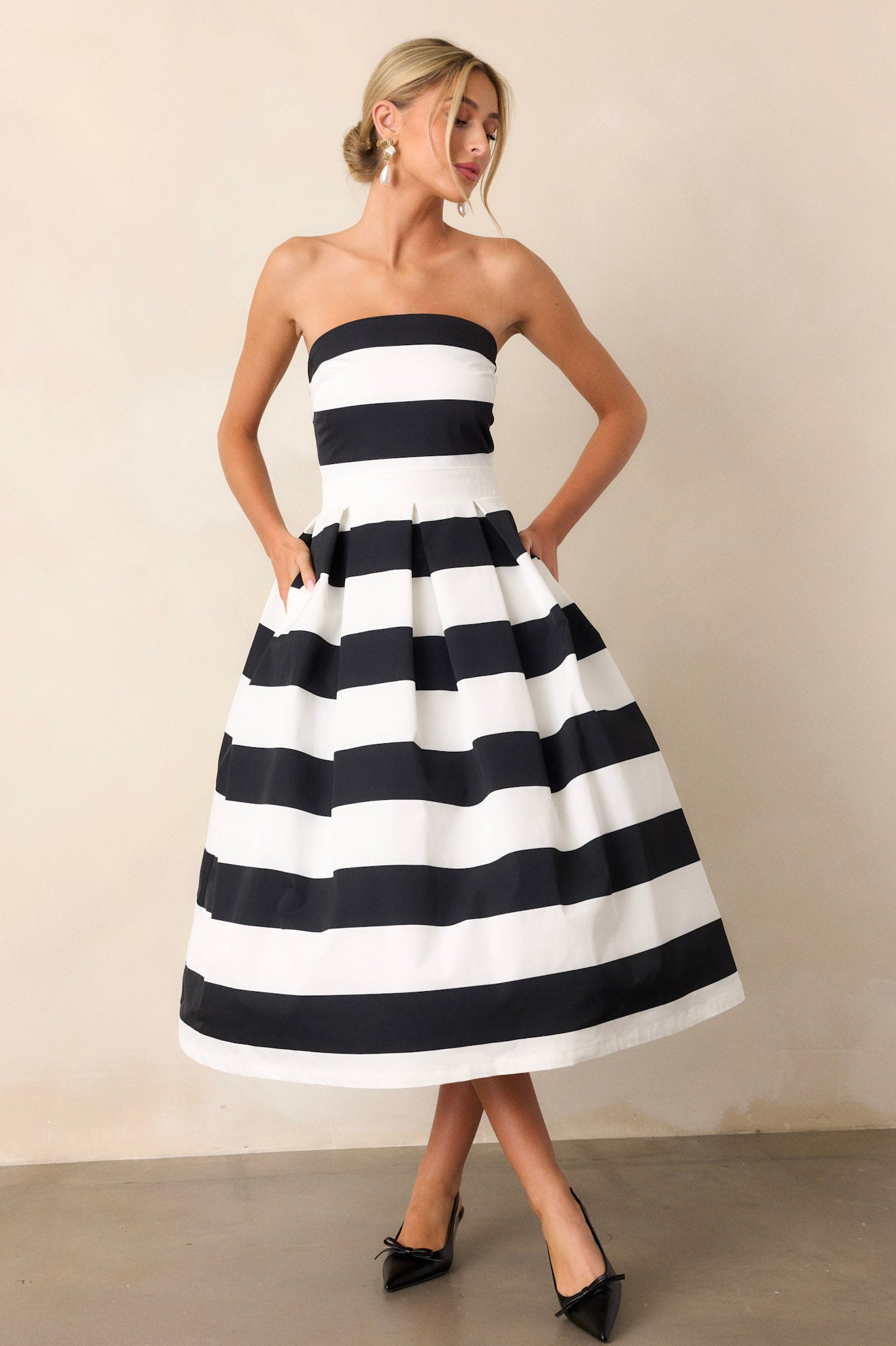 Action shot of the dress capturing the flow and structure of the fabric, highlighting the strapless neckline, thick waistband, and the timeless stripe pattern.