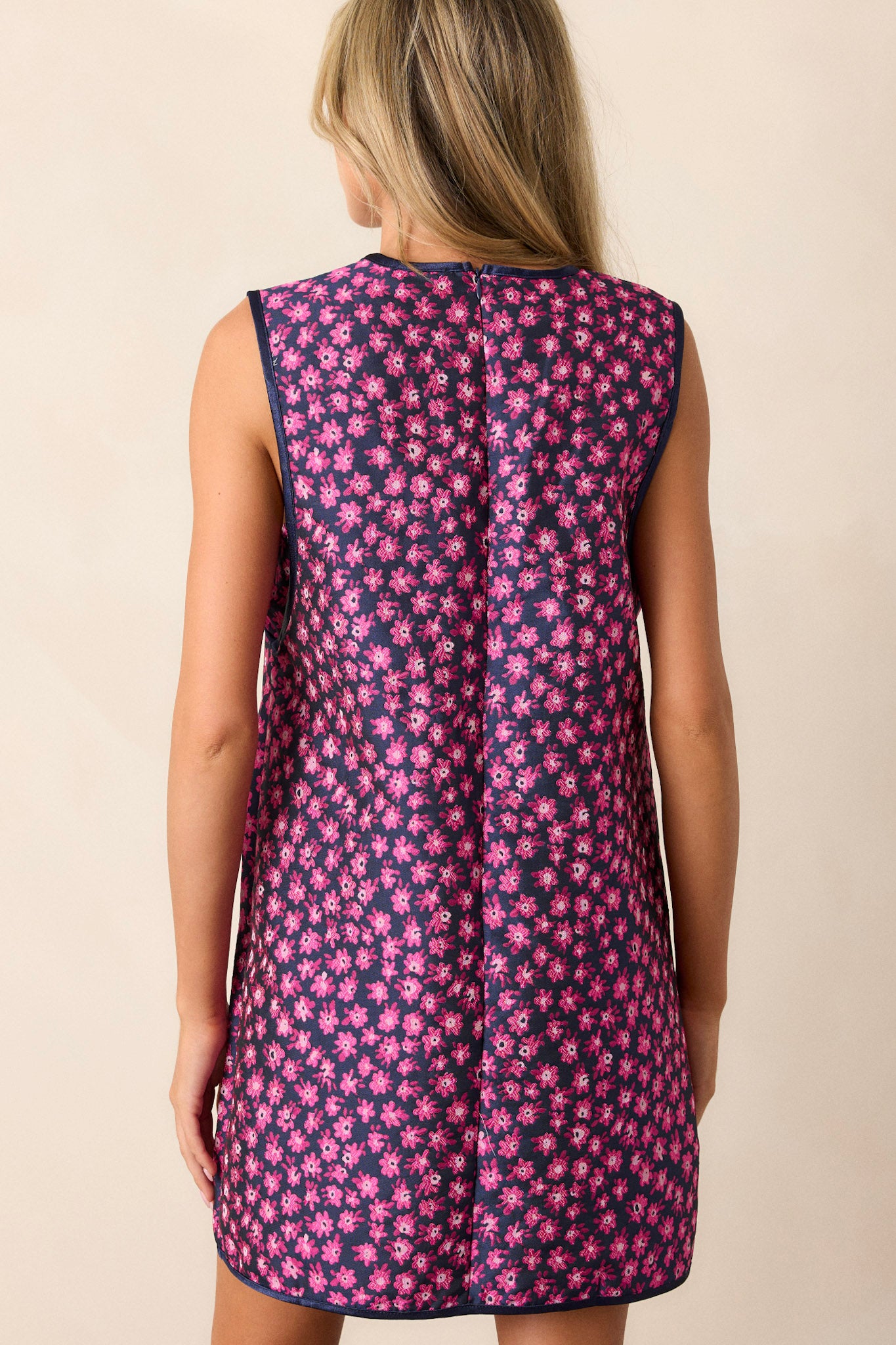 Back view of a magenta mini dress highlighting the discrete back zipper, brown trim, and the overall structure of the dress.