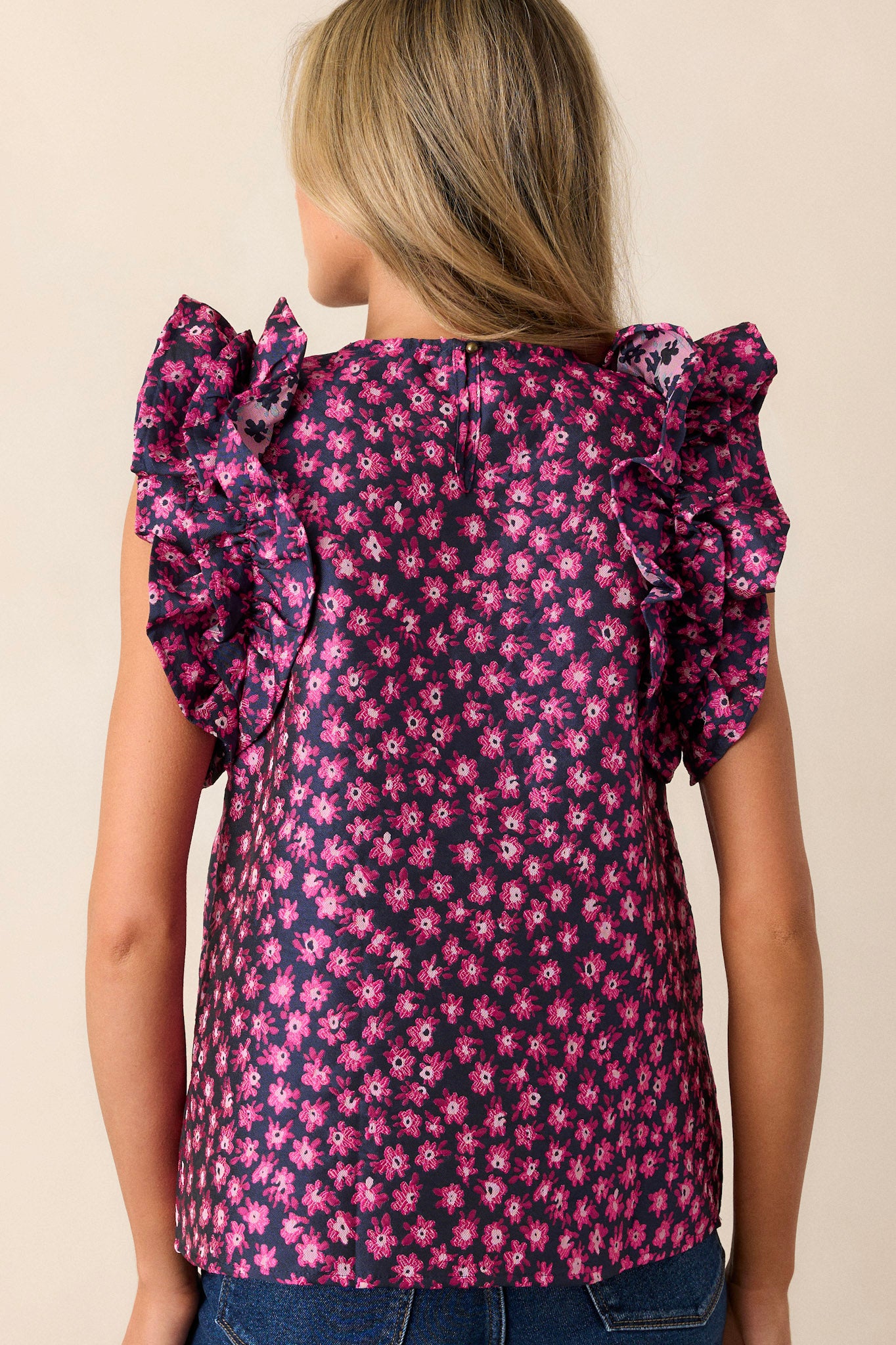 Back view of the navy floral top highlighting the ruffled sleeveless design and the smooth fit of the fabric across the back.