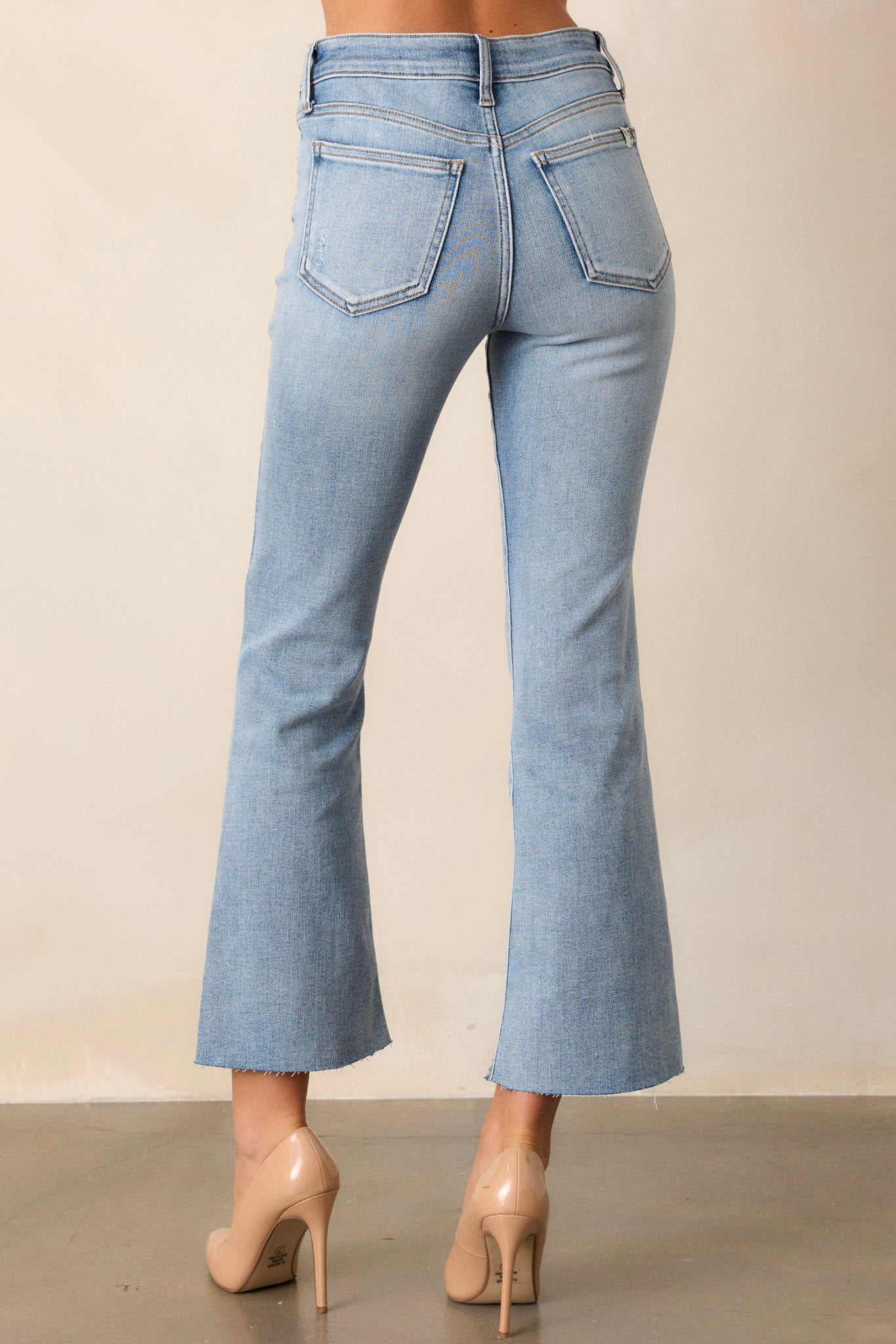 Back view of the pants highlighting the functional back pockets, the light washed denim, and the cropped flare leg