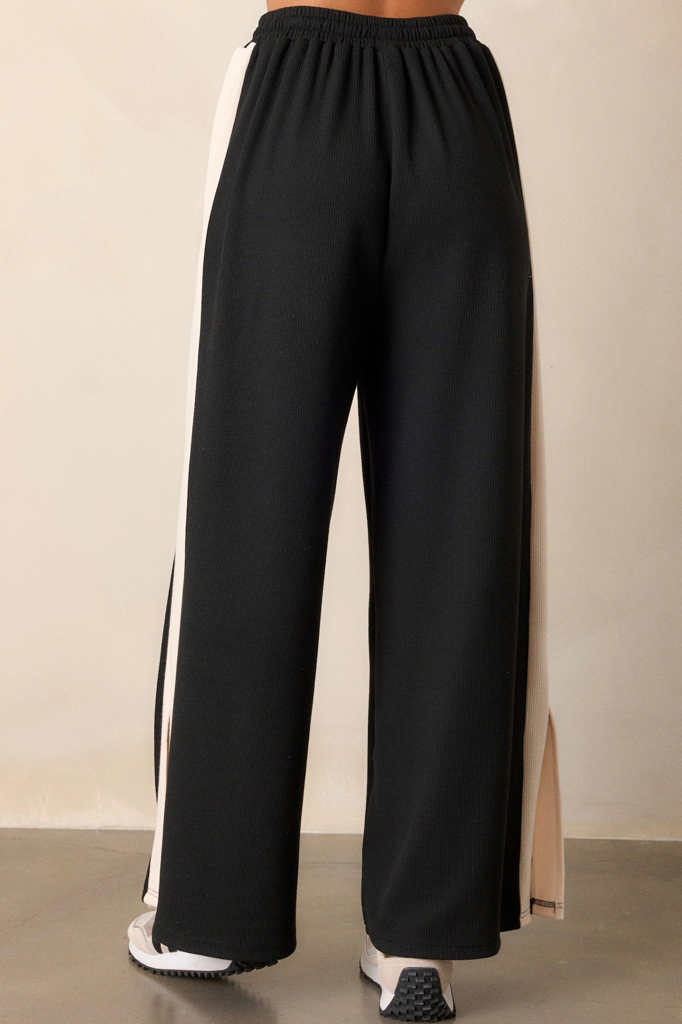 Back view of the black and ivory pants highlighting the elastic waistband, high waisted design, and the white trim that continues down the back of the legs