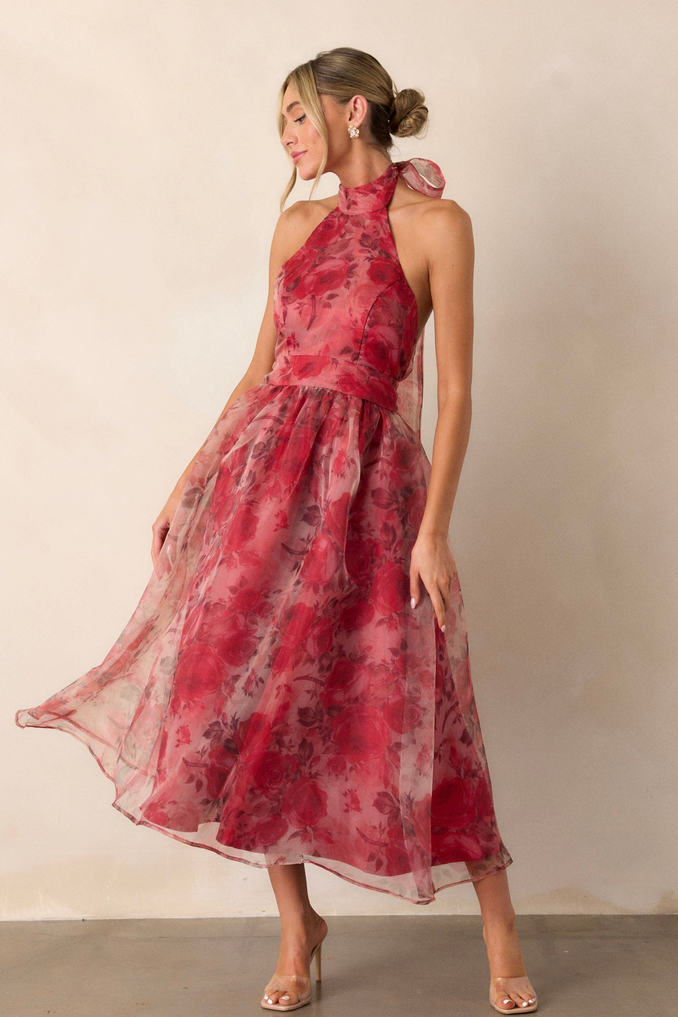 Angled view of the red floral dress displaying the halter-neck design, the floral mesh pattern, and the low back, emphasizing the dress's graceful silhouette