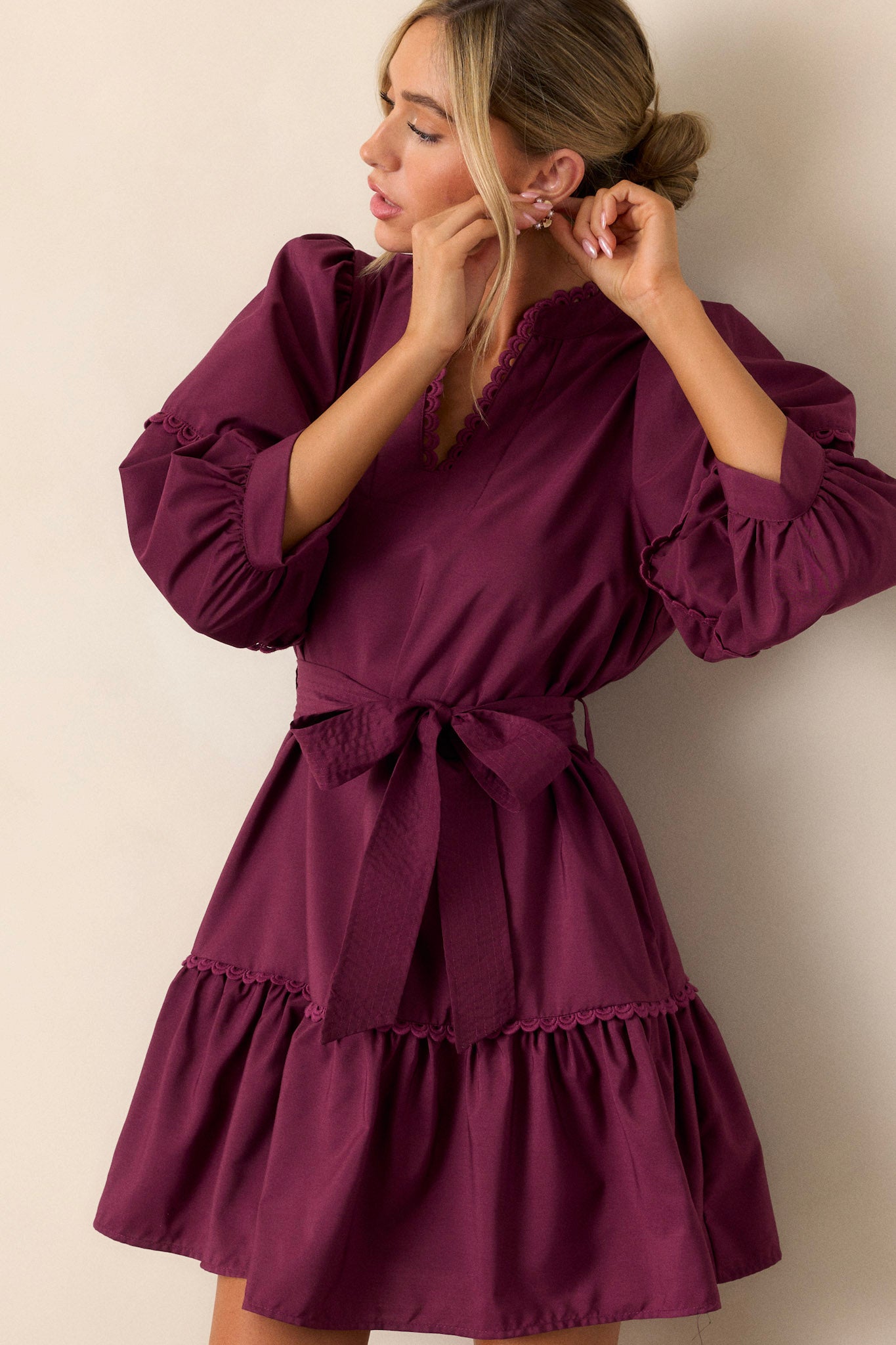 This plum mini dress features a split neckline, a scalloped detailing on the neckline and collar, a self-tie drawstring belt, functional hip pockets, a tiered design, scalloped detailing and tiered bishop sleeves.