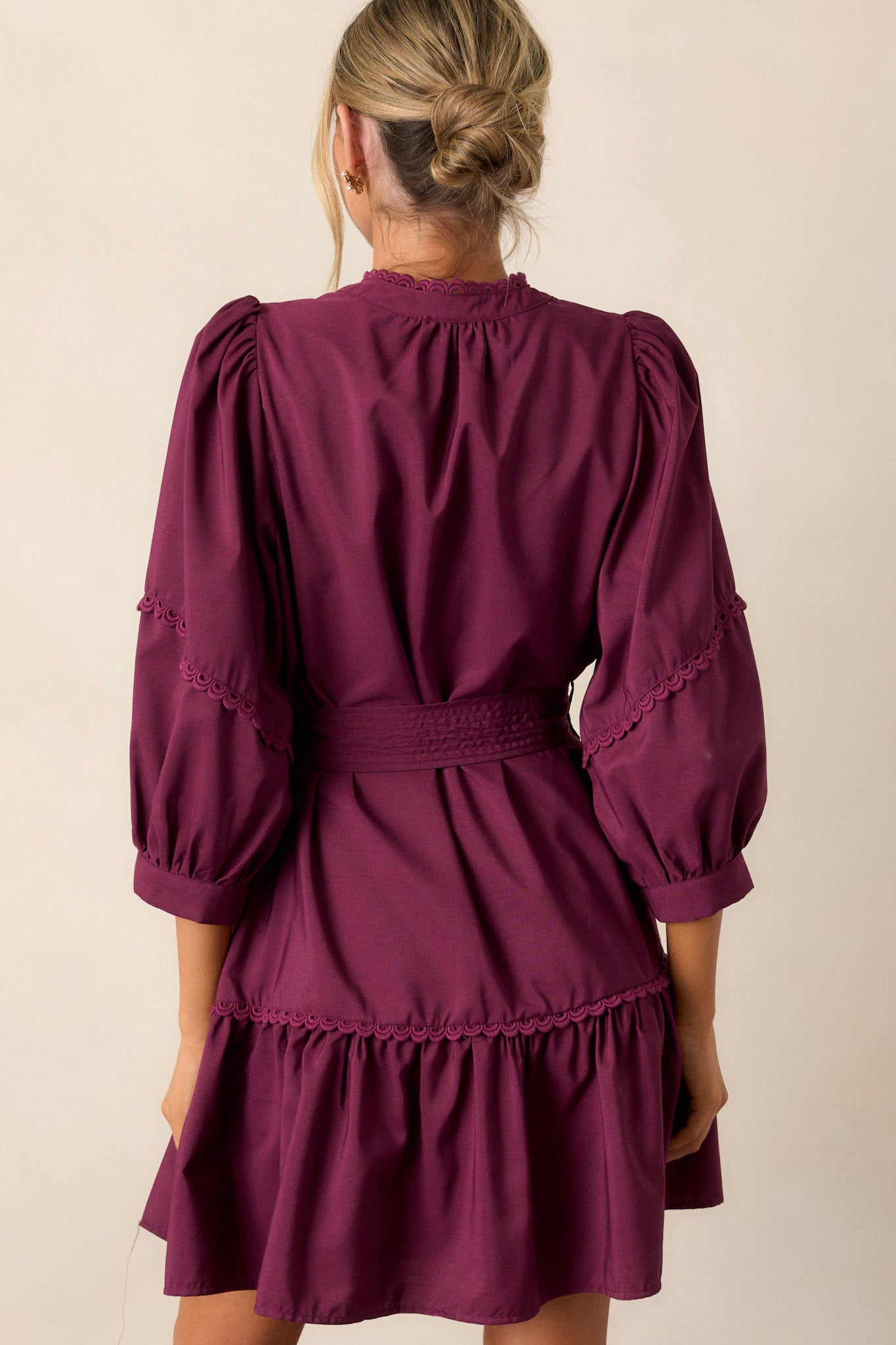 Back view of the plum mini dress highlighting the tiered design, the scalloped detailing on the neckline and sleeves