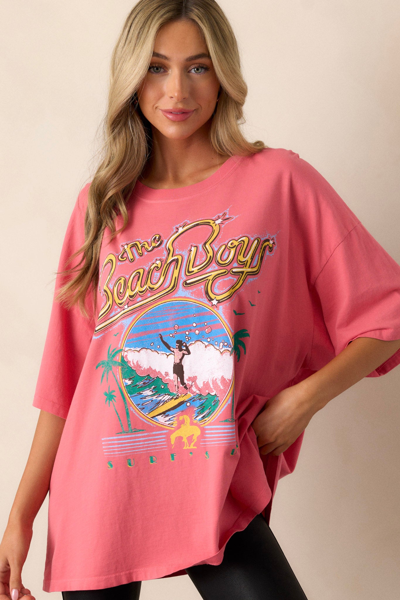 Close-up of crew neckline on pink tee with colorful 'The Beach Boys' graphic and soft cotton fabric.