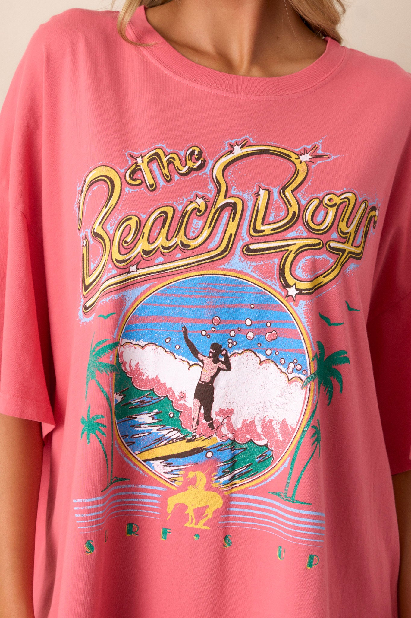 Close-up of soft cotton fabric on pink tee, featuring vibrant 'The Beach Boys' graphic with fine details.