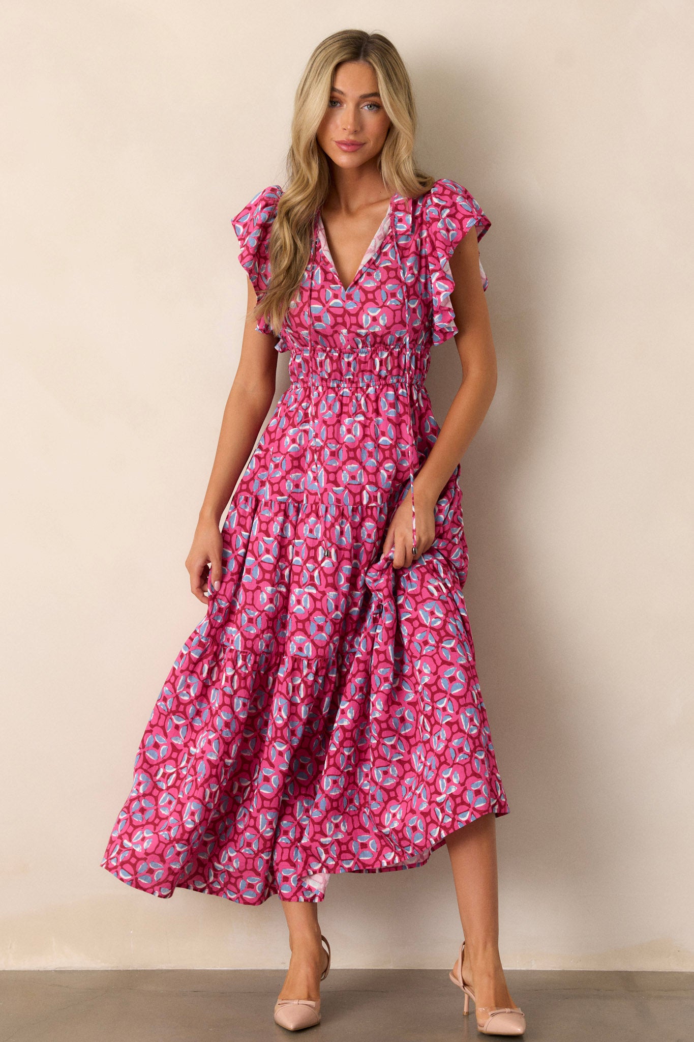 Action shot of the pink maxi dress capturing the movement of the fabric and the flow of the tiered design, highlighting the ruffled v-neckline, elastic waistbands, and short ruffle sleeves.