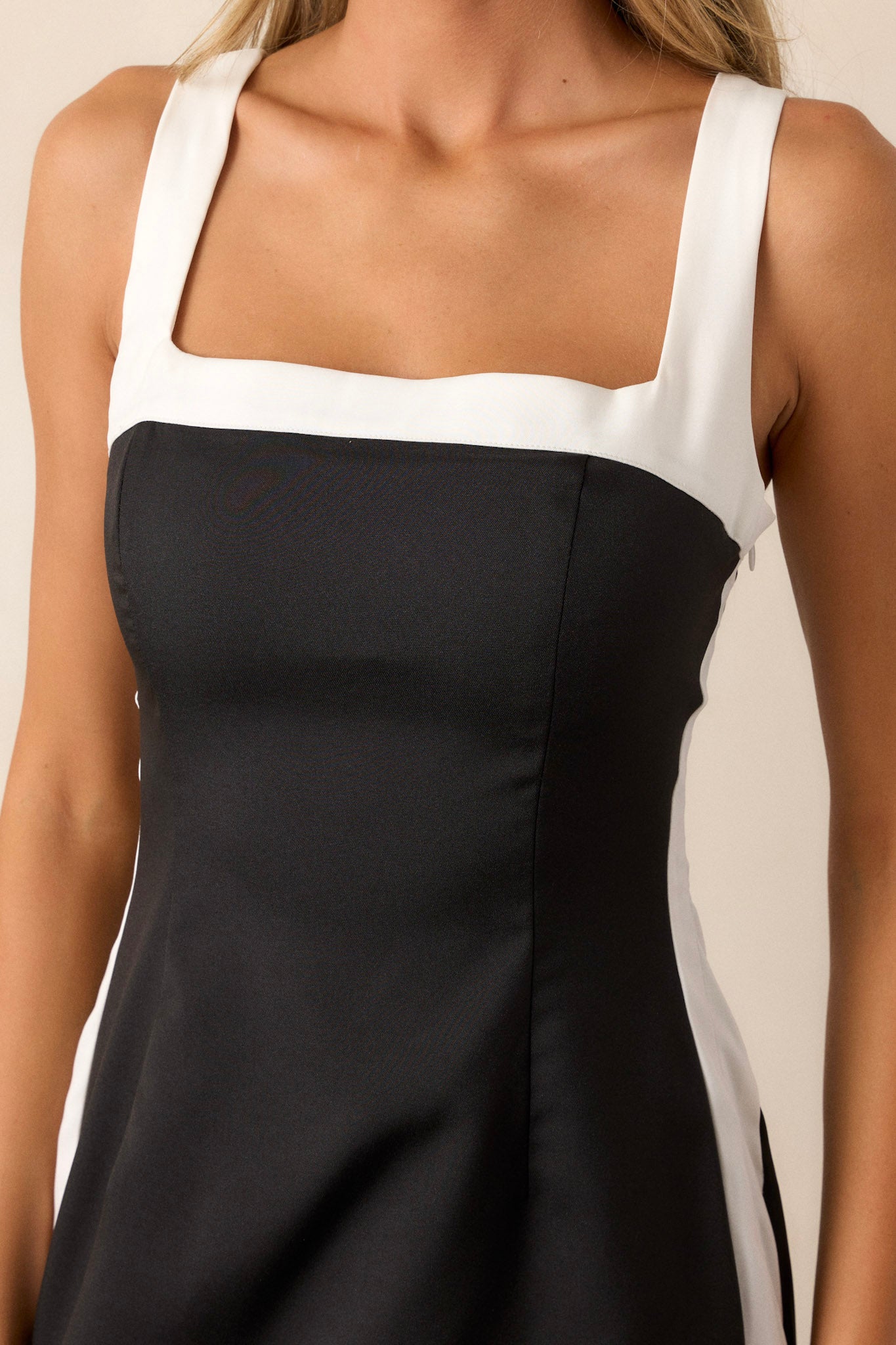 A close-up image showing the texture of the black fabric and the detailing of the white color-blocked trim along the sleeves and sides.