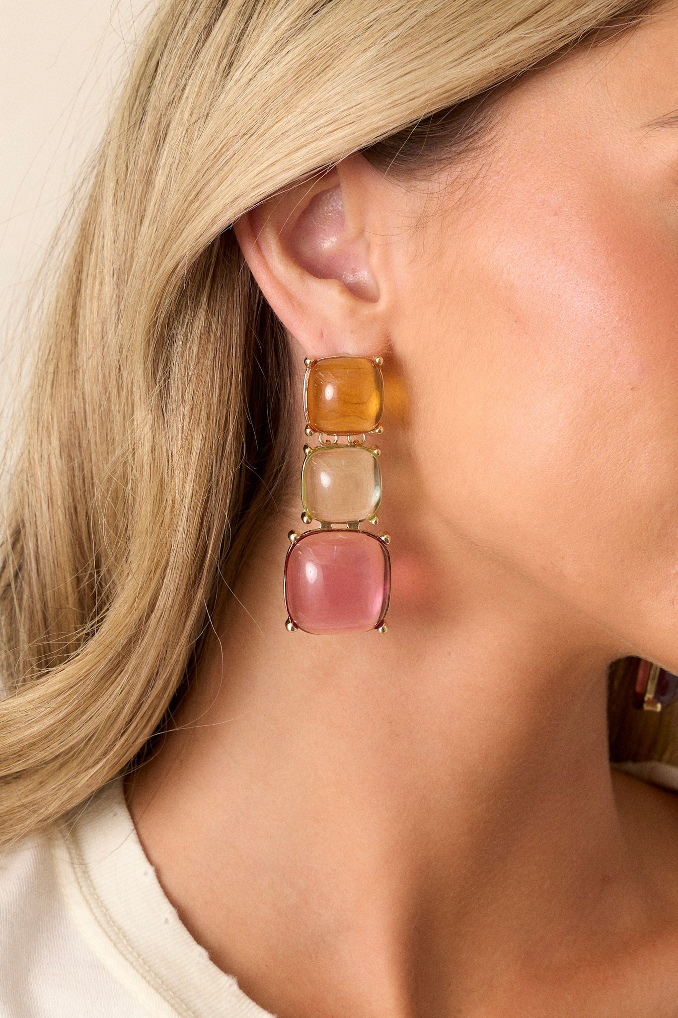 These earrings feature gold hardware, an orange stone stud, green and pink drop stones, and a secure post backing.