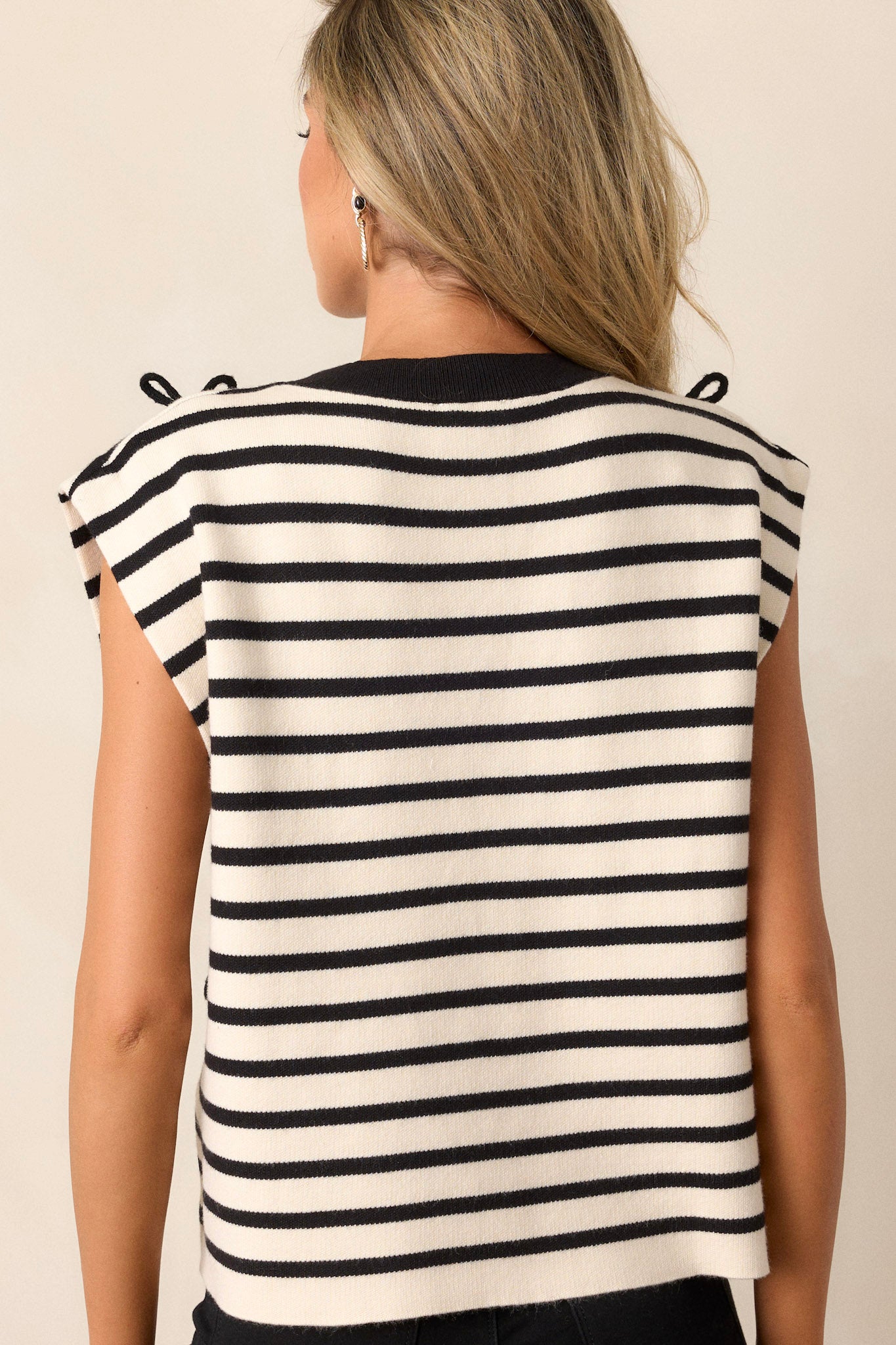 Back view of this black stripe top that features a high rounded neck, a black and white striped design, knitted black bow details on the front, a soft knitted texture and cap sleeves.