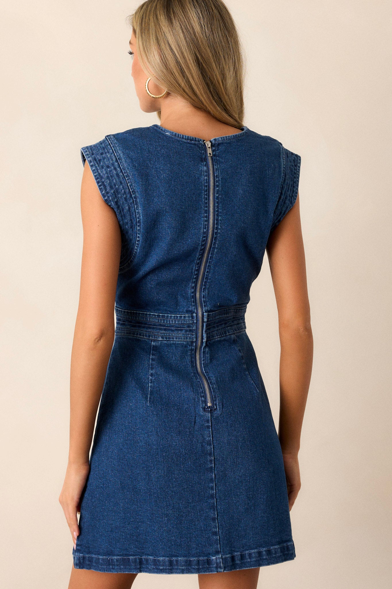 Back view of the denim dress, focusing on the zipper closure and the continuation of the structured seams and cap sleeves.