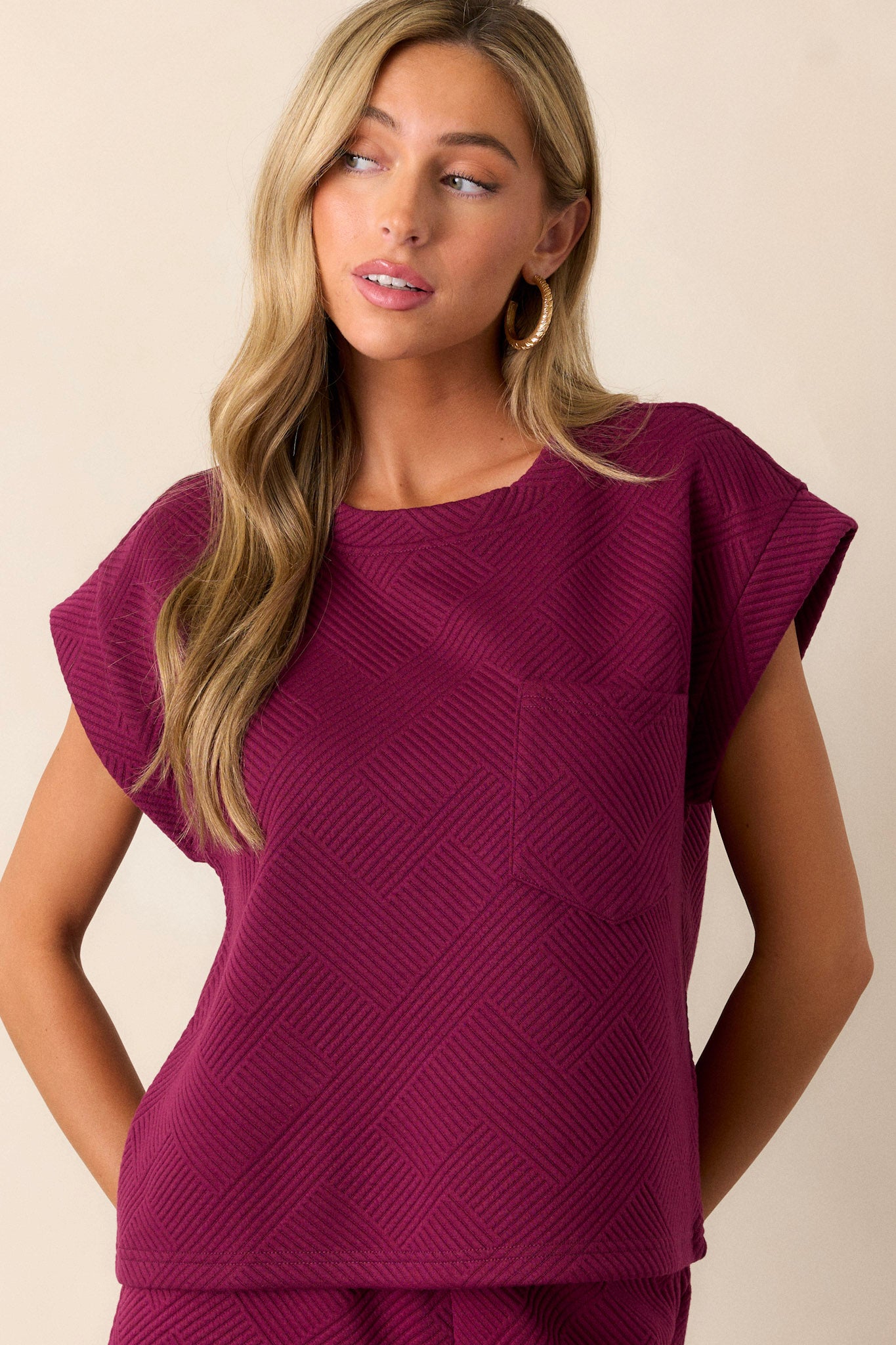 This sangria purple top features a crew neckline, a functional breast pocket, subtle crisscross texturing, and wide cuffed short sleeves.