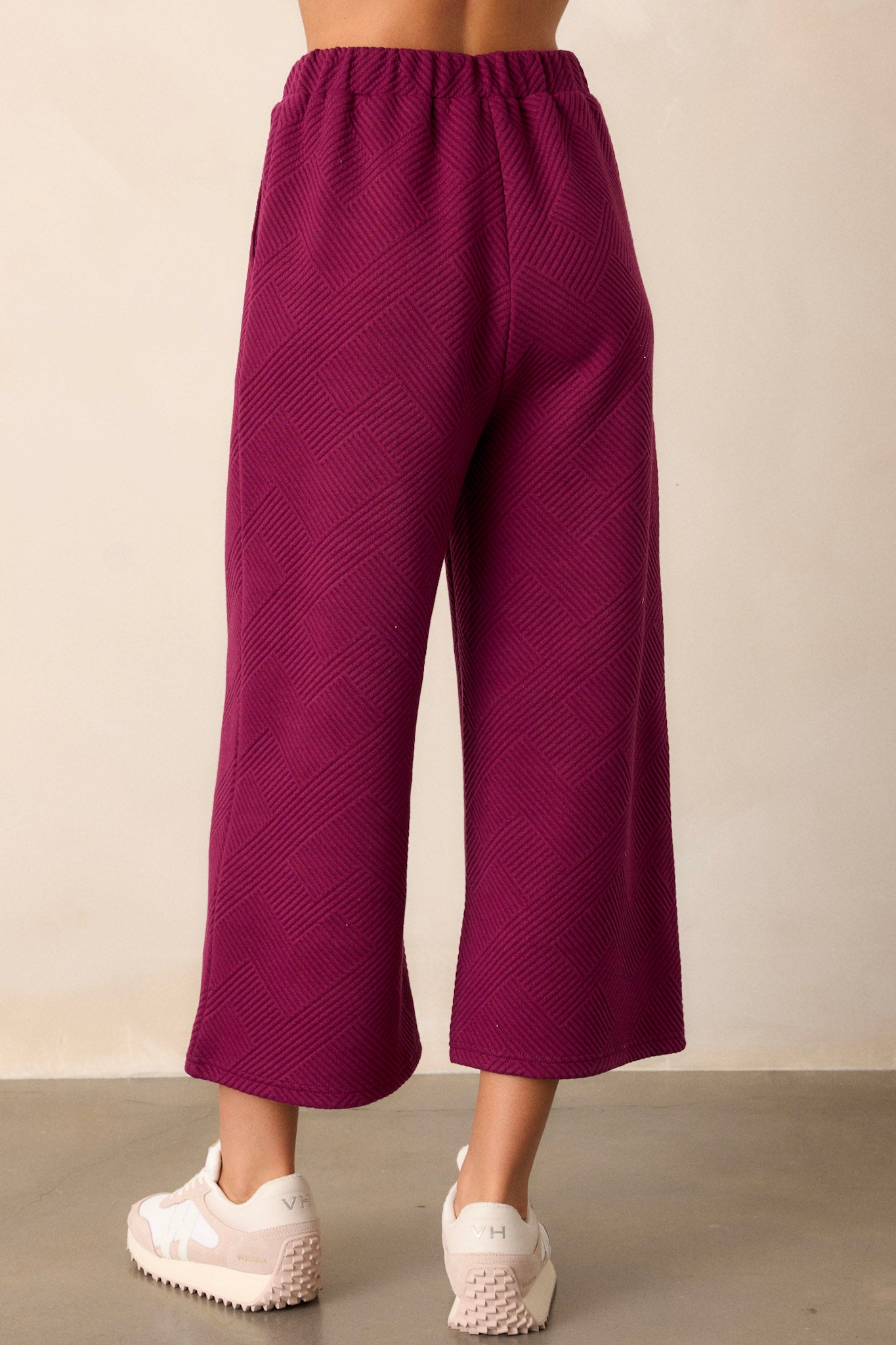 Back view of sangria purple pants highlighting the elastic waistband, wide leg design, and the continuation of the textured crisscross pattern.