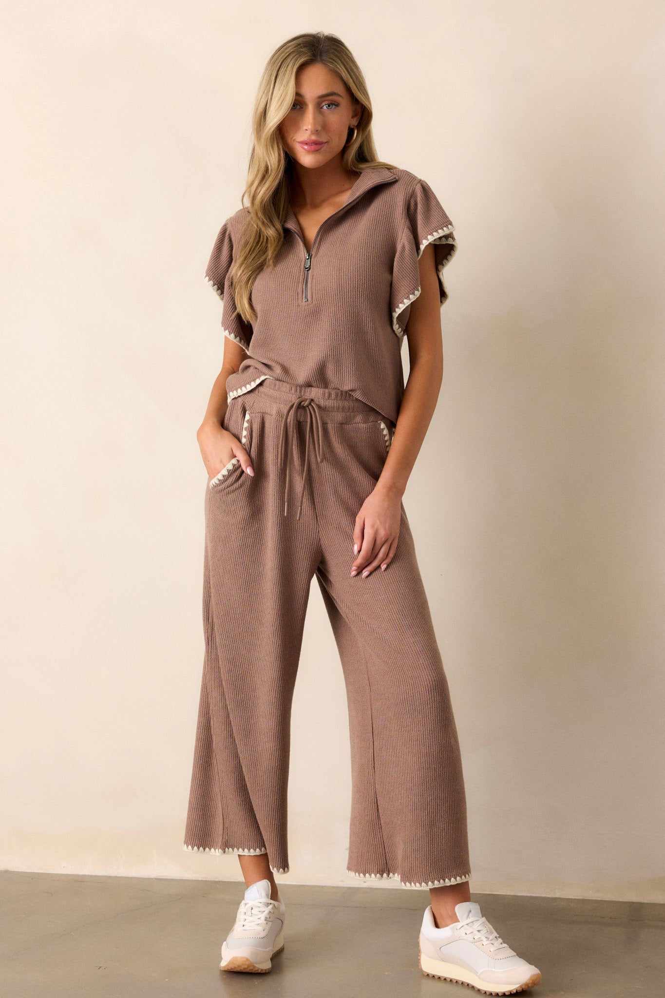 Full body of these mocha pants that feature an elastic waistband, an optional waist drawstring, an ivory ruffle trim, functional hip pockets, a soft stitched material and a wide leg