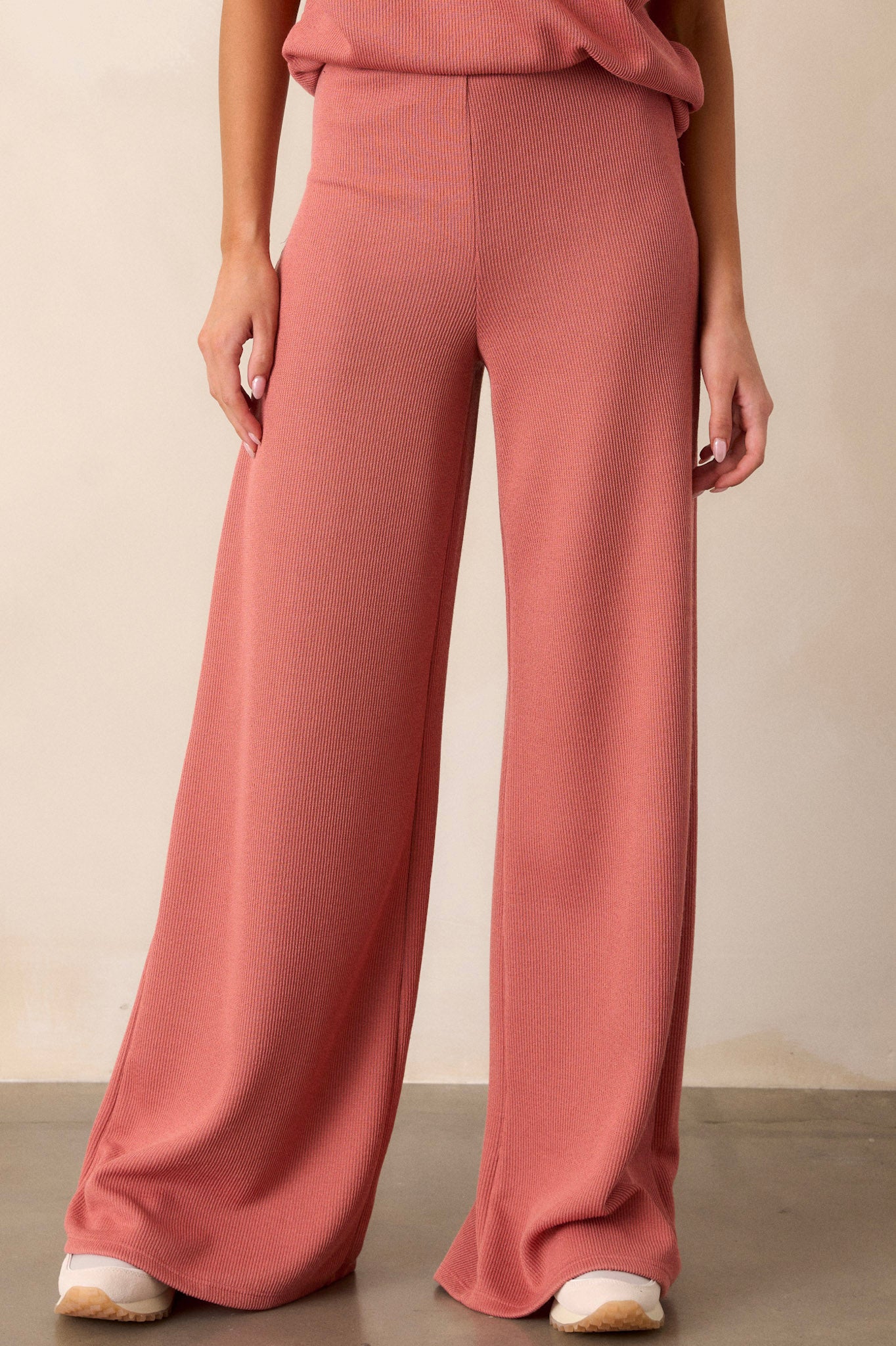 Front view of these coral knitted pants that feature an elastic waist band, a high waisted design, a knit towel like texture on the outside, a soft inside and a wide leg.