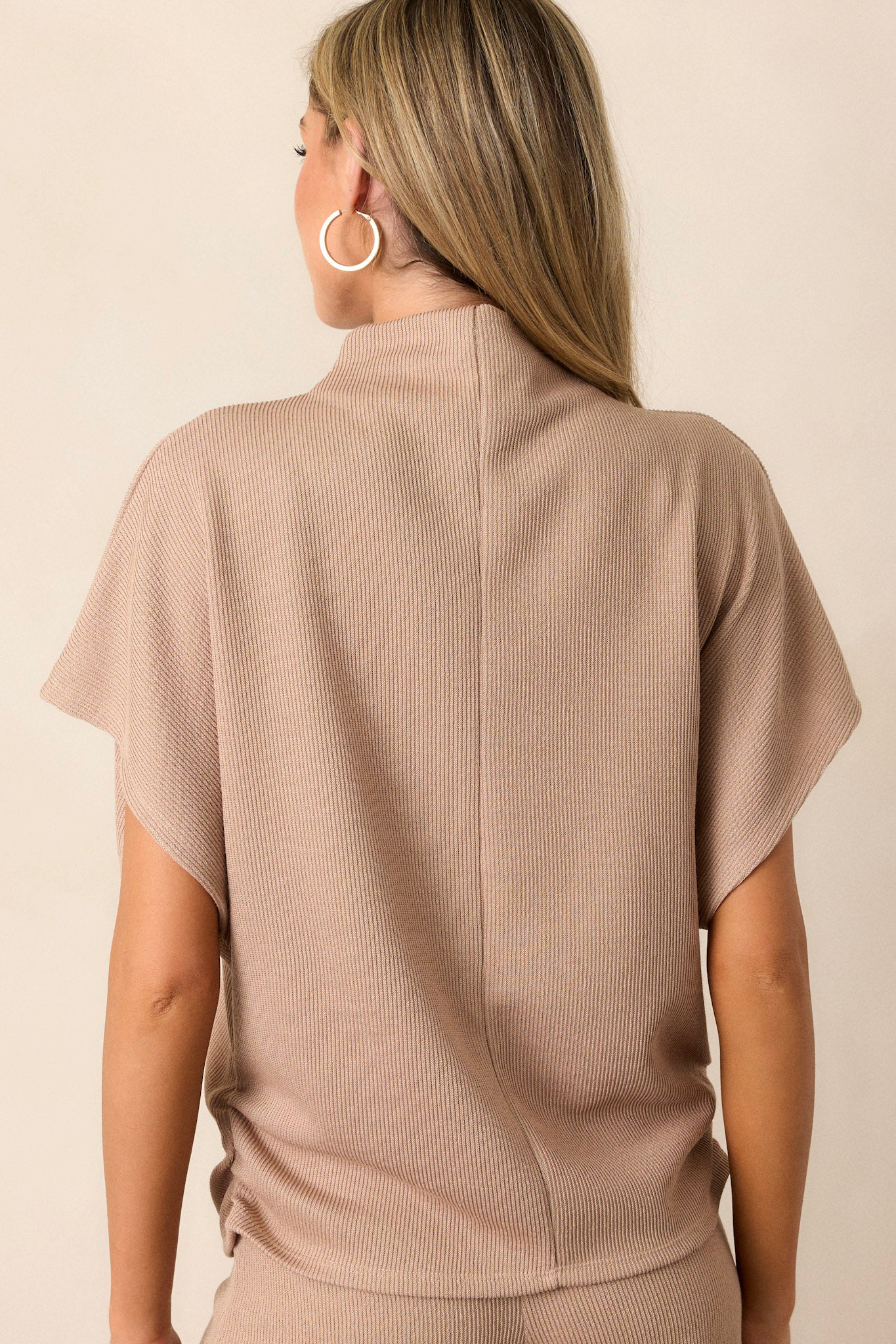 Back view of the beige top highlighting the knit towel-like texture, the cinching at the hips, and the smooth inside fabric.