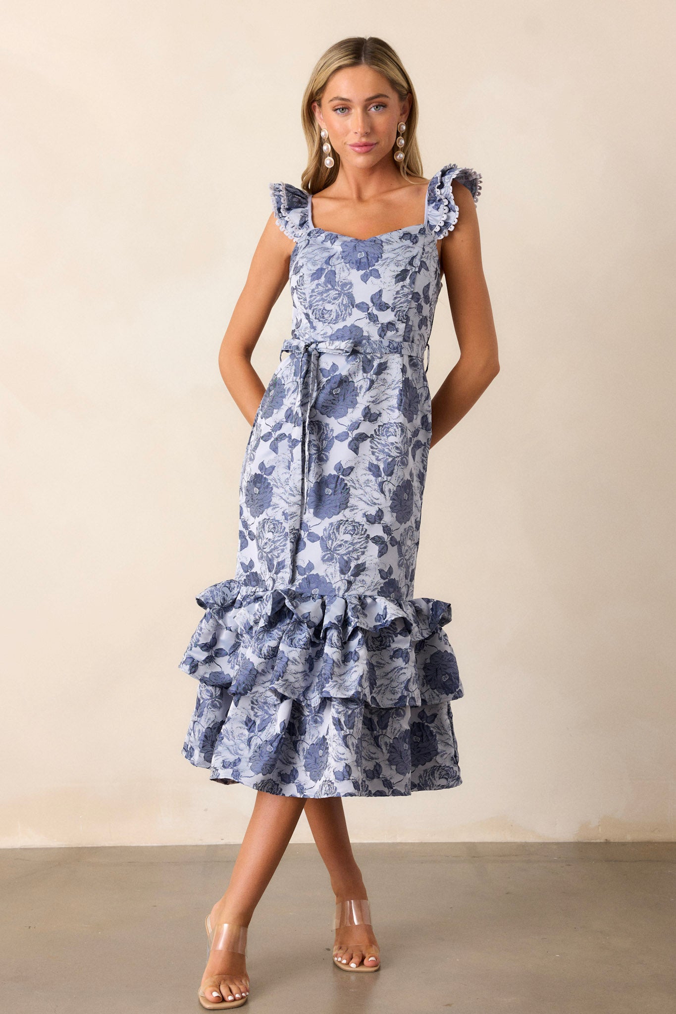 Full length view of the dress featuring a scoop neckline, a ruffled puffy bottom, a functional tie at the back, and a side zipper for easy on and off.