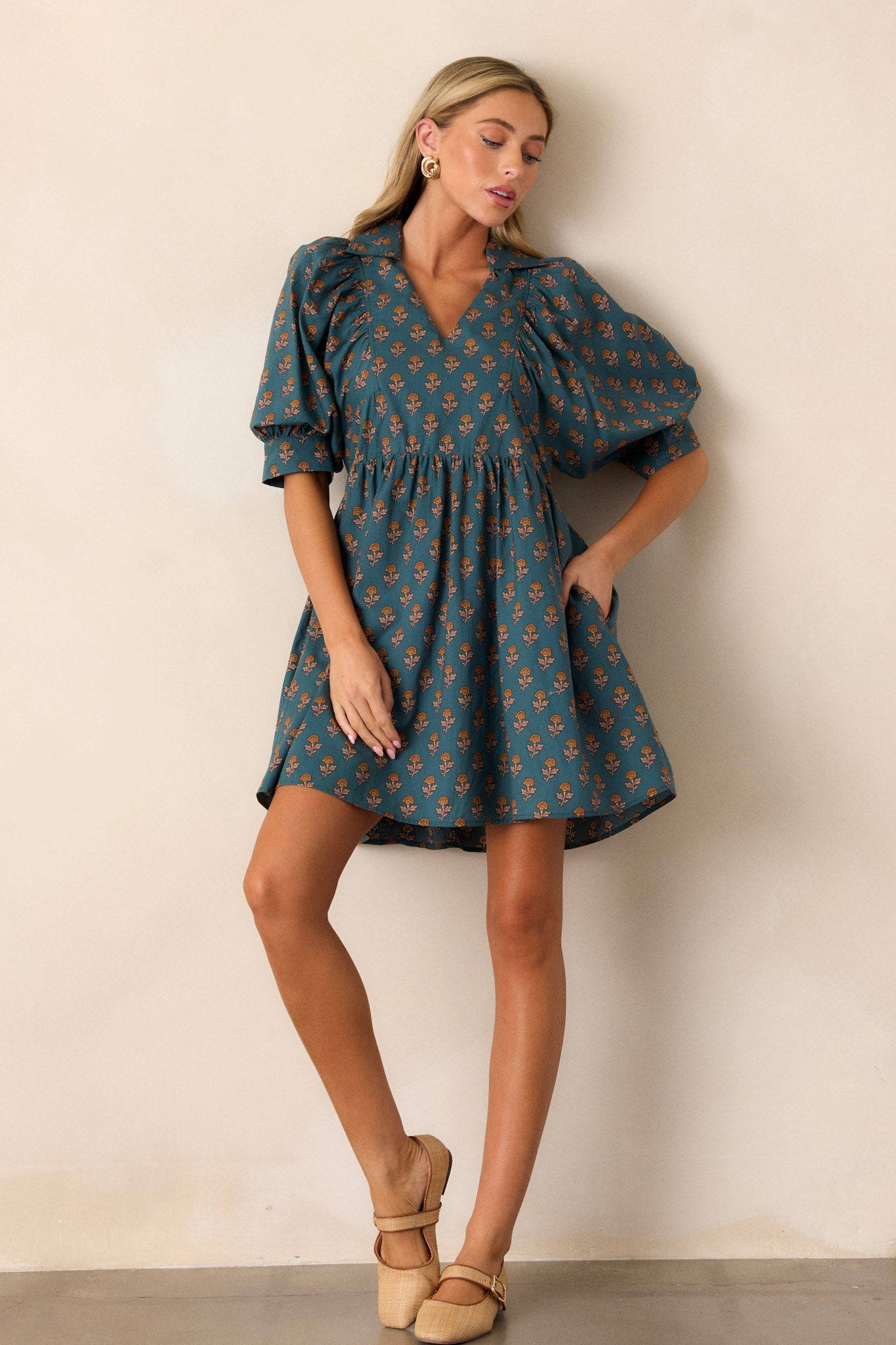 This teal dress features side pockets, a small v-neck and puff sleeves.