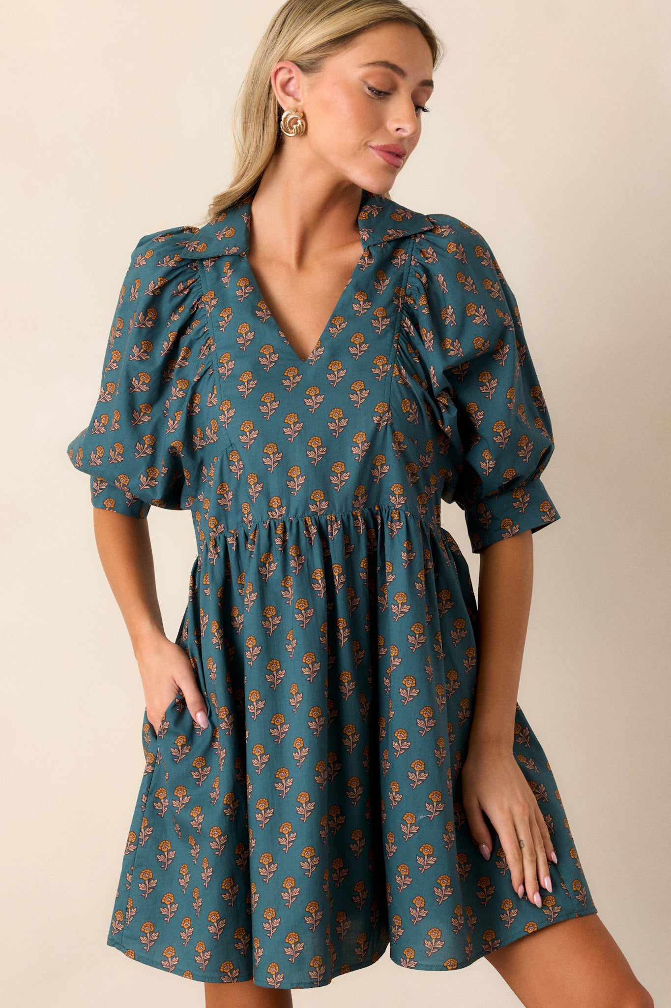 Front angled view of the teal dress showcasing the small v-neckline, puff sleeves, and side pockets