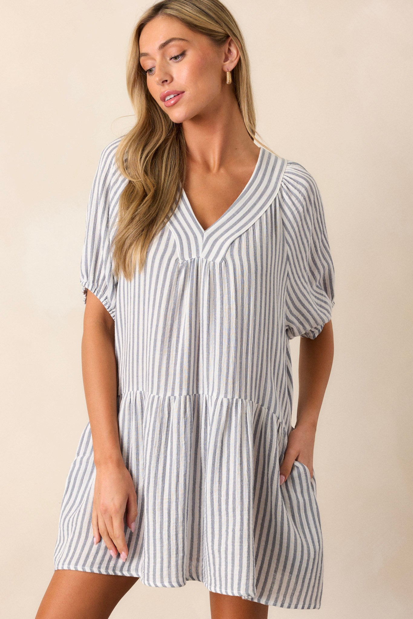 Close-up of the blue stripe mini dress, focusing on the tiered structure and blue and ivory pattern, with visible hip pockets.