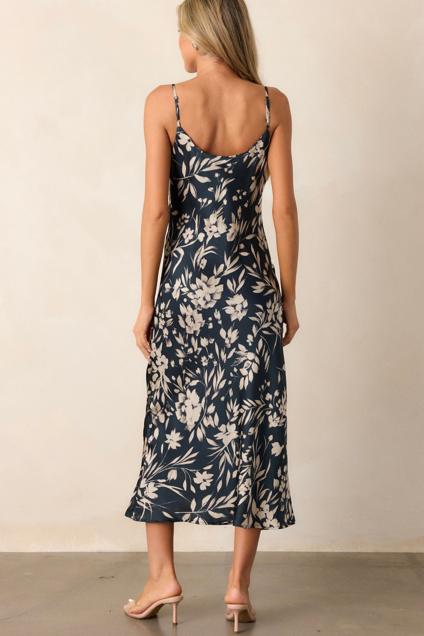 Back view of the dark teal dress highlighting the adjustable straps, the smooth back design, and the ivory floral print extending down the length of the dress.