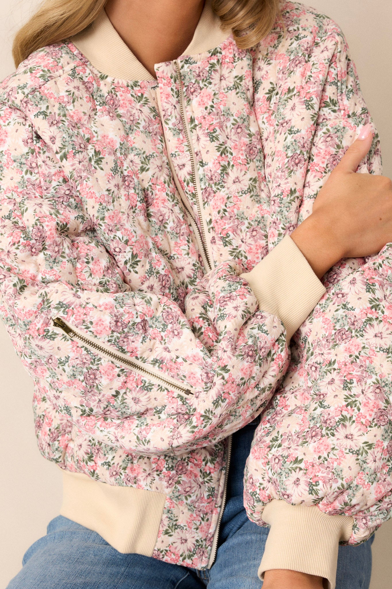 Close-up view of this pink floral jacket that features a full zip front, functional waist pockets, a functional zipper pocket on the right sleeve.