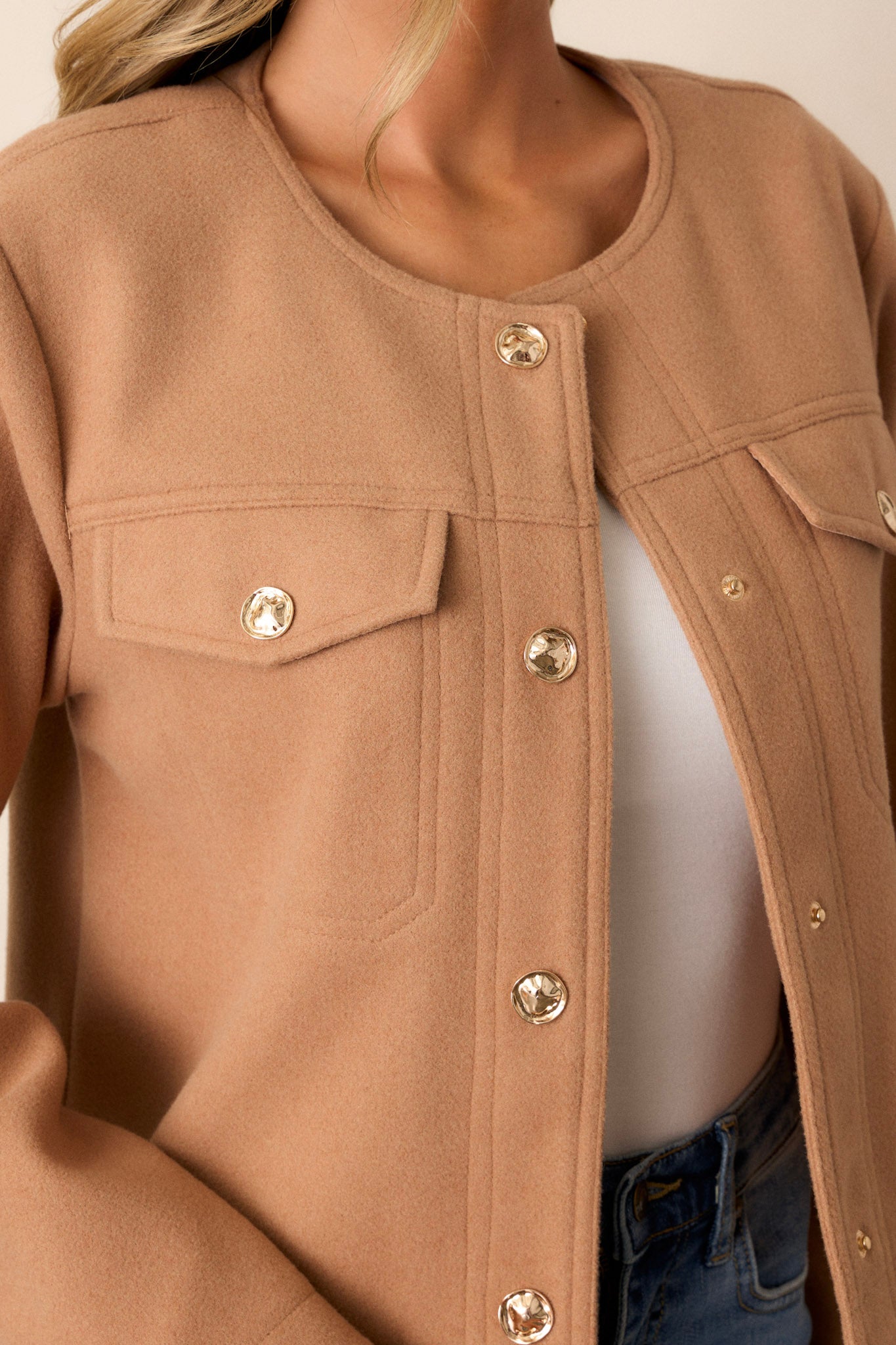 This camel brown jacket features gold hardware, a scoop neck, two functional breast pockets, and a cozy tweed fabric.