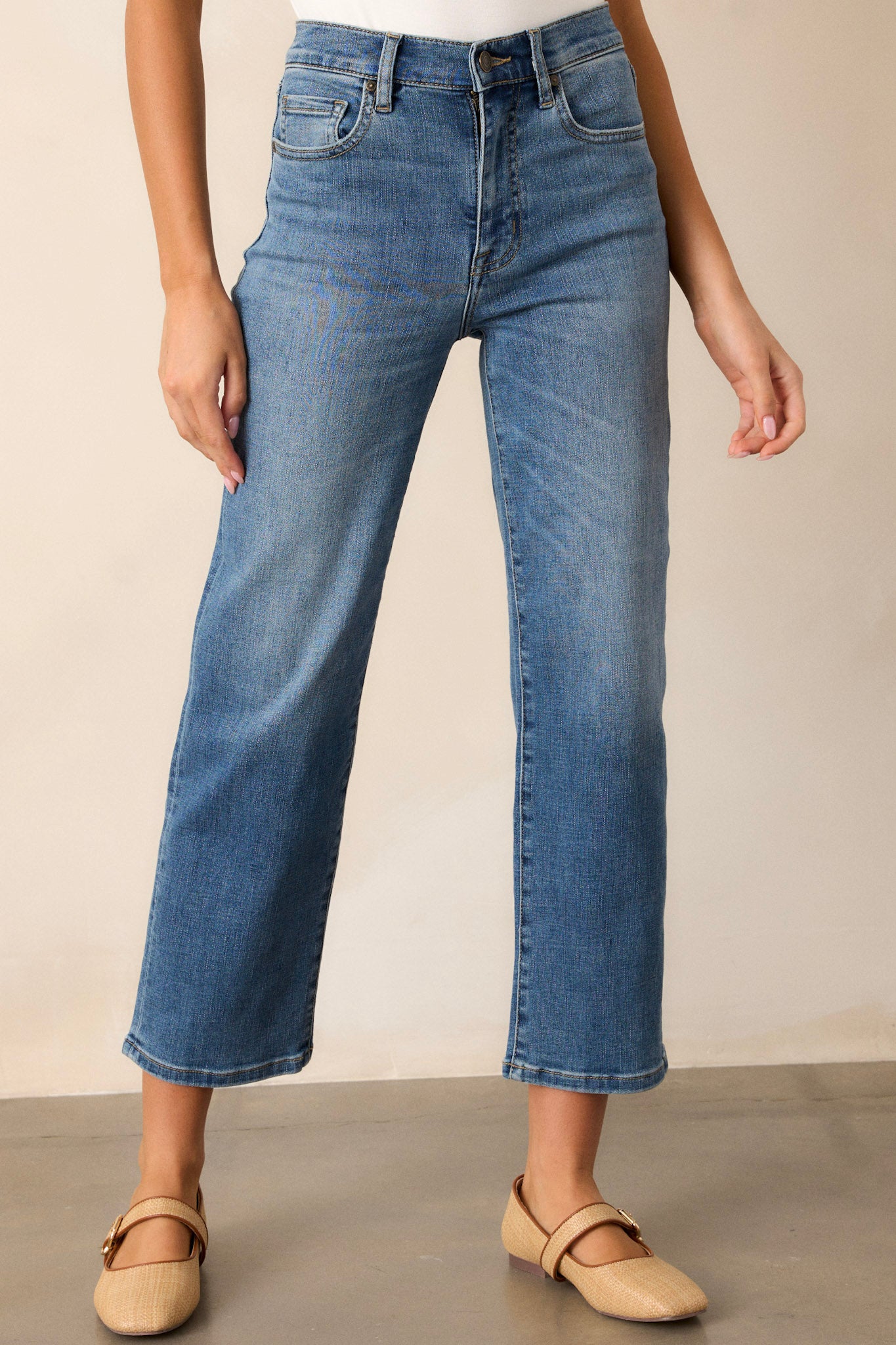 Front angled view of dark wash straight leg jeans featuring a high waist design, functional front & back pockets, a button & zipper closure, and a straight leg