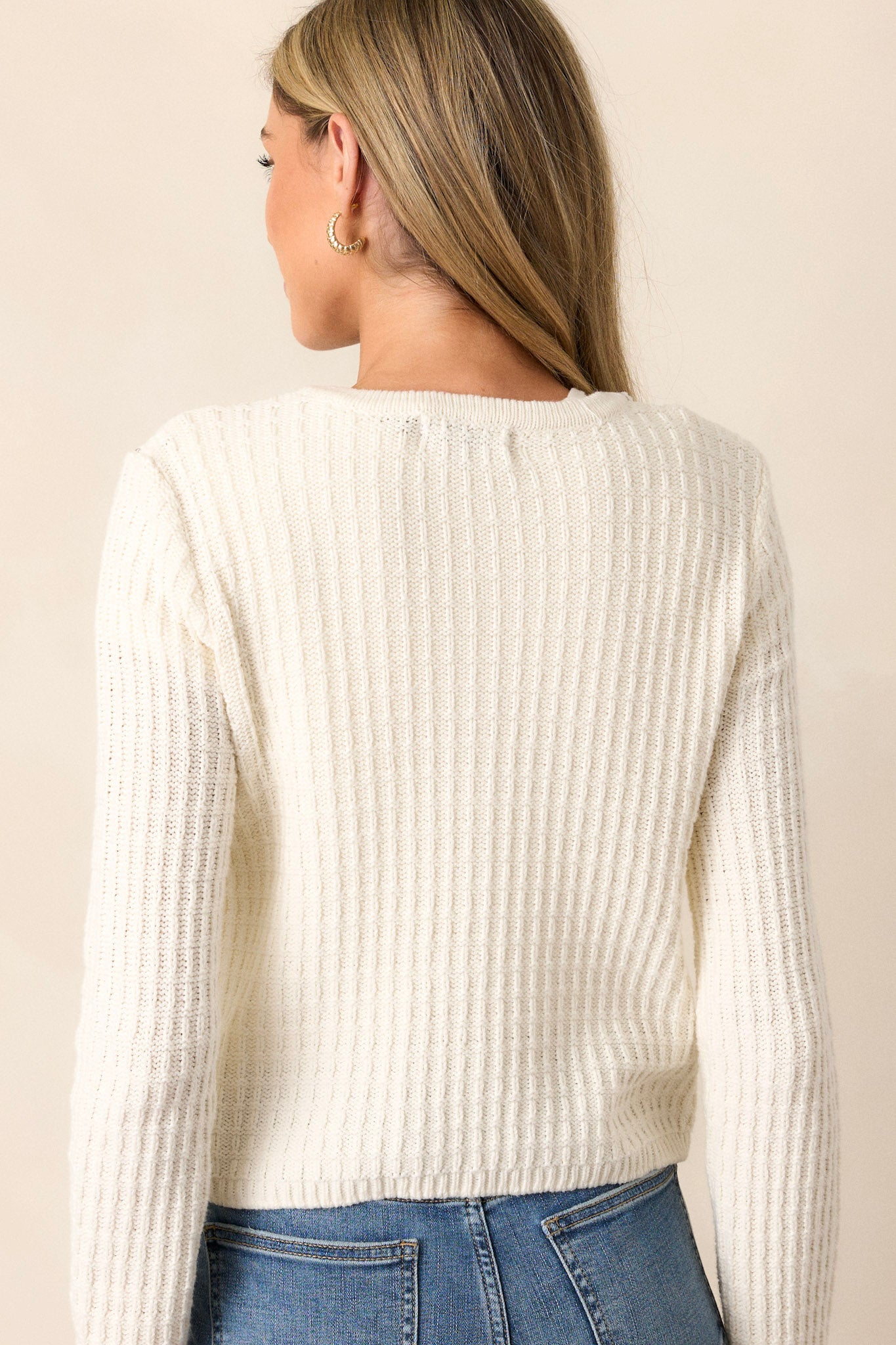 Back view of the ivory sweater highlighting the ribbed knit design and the clean, seamless back without additional detailing