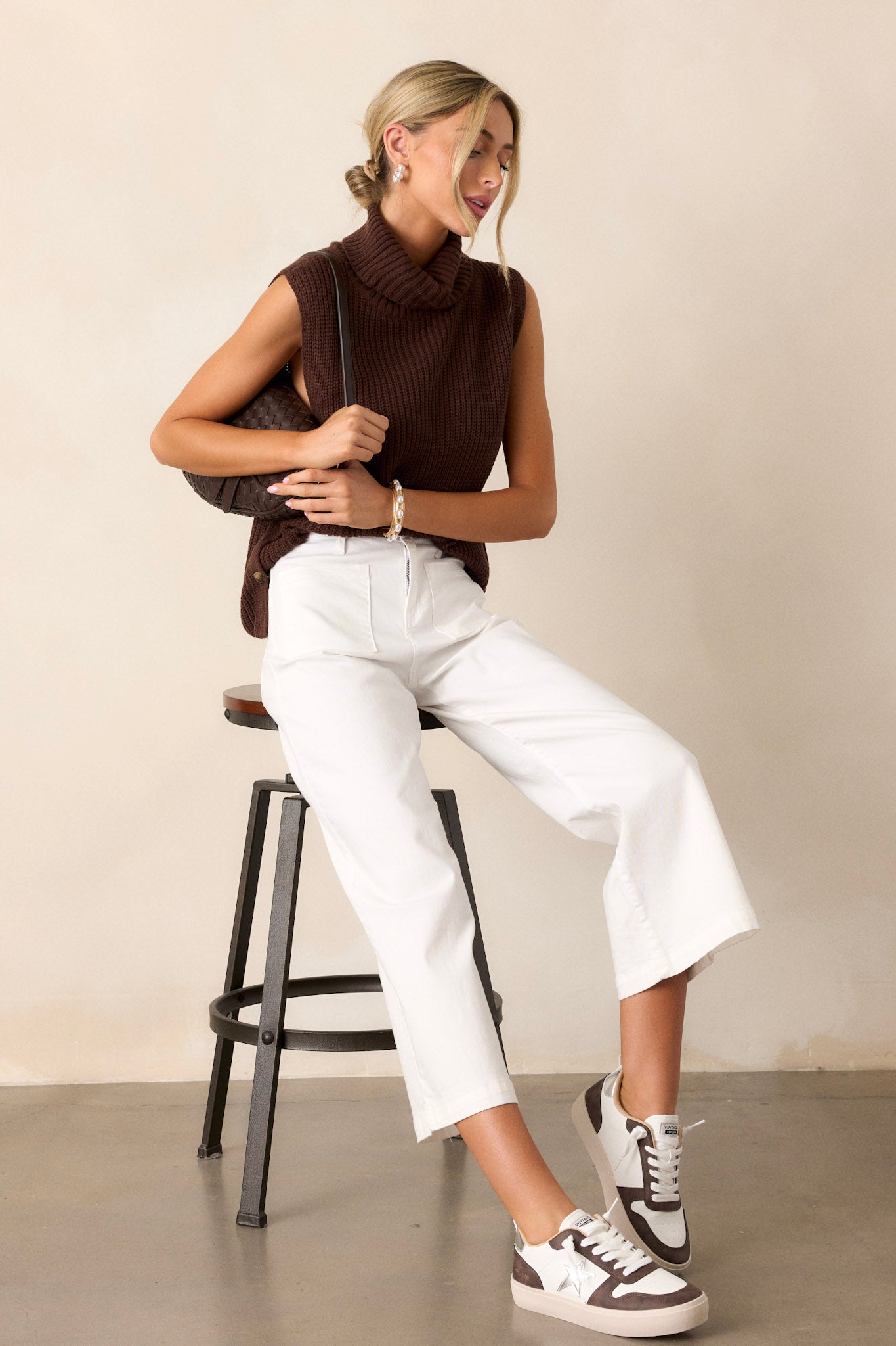 Full length view of white jeans with a high waisted design, a button & zipper closure, belt loops, functional front & back pockets, a cropped hemline, and a flared leg