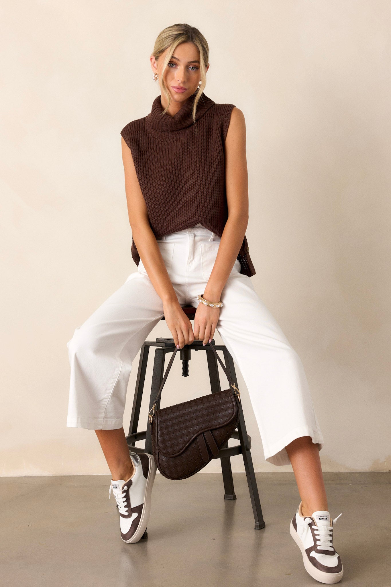 A full-length view of the brown sweater featuring a turtleneck and sleeveless design, showcasing its stylish silhouette.