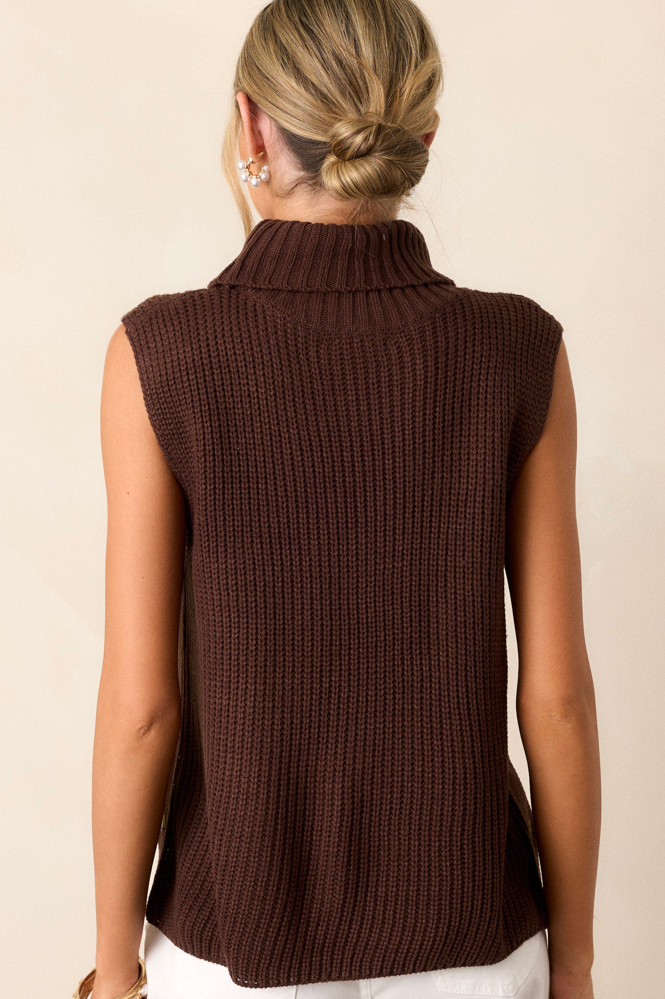 A view of the back of the brown sweater, highlighting the simplicity of the sleeveless design while showcasing the ribbed texture throughout.