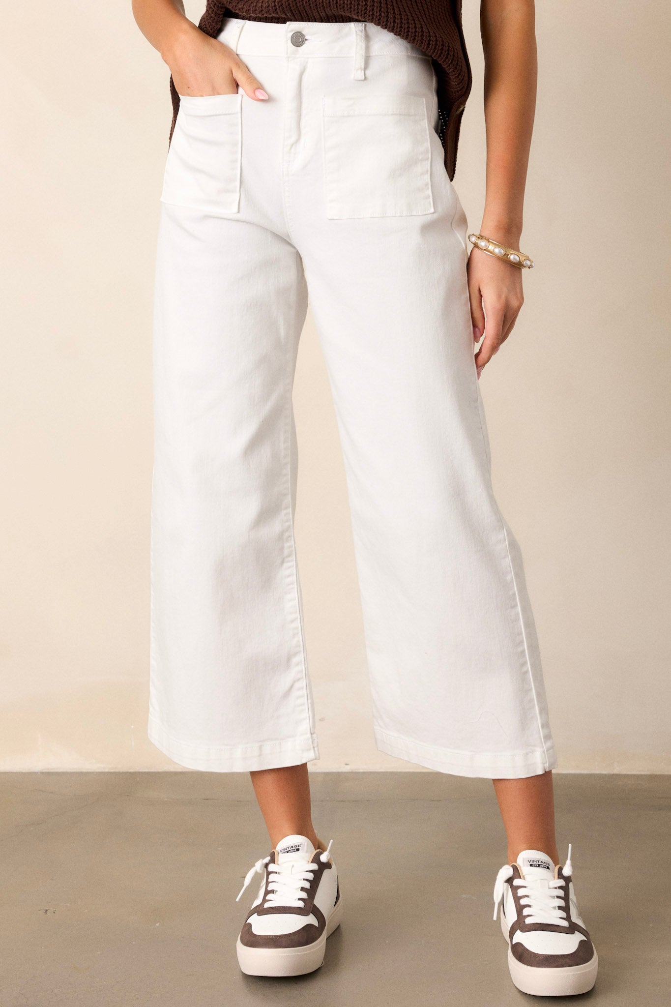 Front view of white jeans featuring a high waisted design, a button & zipper closure, belt loops, functional front & back pockets, a cropped hemline, and a flared leg.