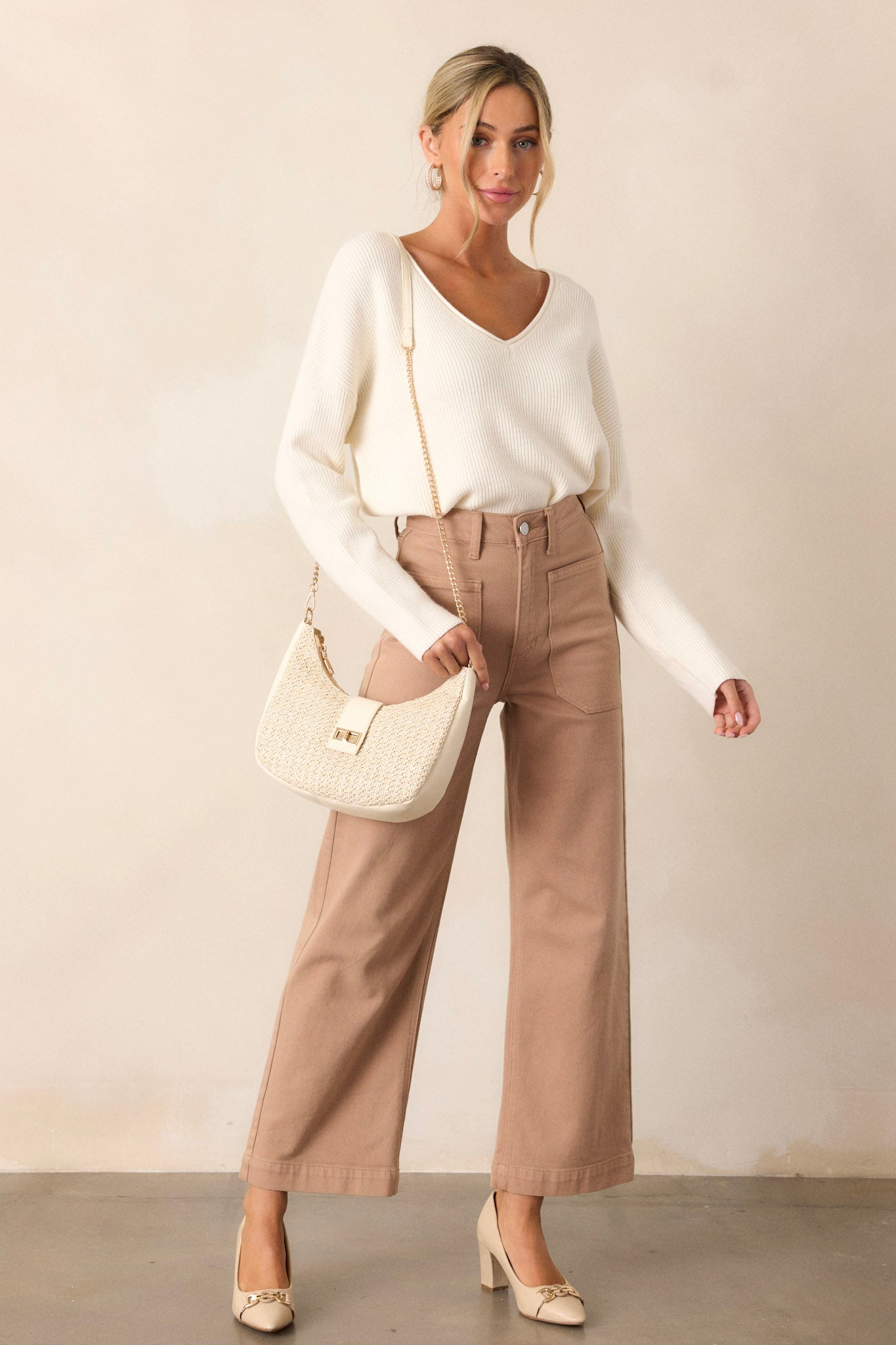 Full body view of an ivory sweater featuring a ribbed design, a v-neck and comfortable fabric.