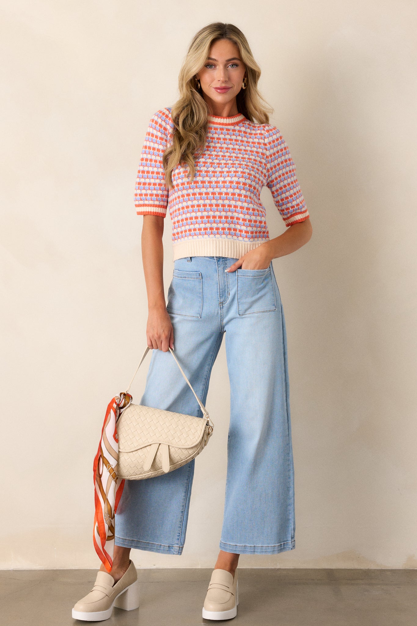 Full-length view of a model wearing the ivory stripe sweater, emphasizing the ribbed high neckline, multi-color stripe design, soft knit texture, ribbed hemline, and short sleeves.