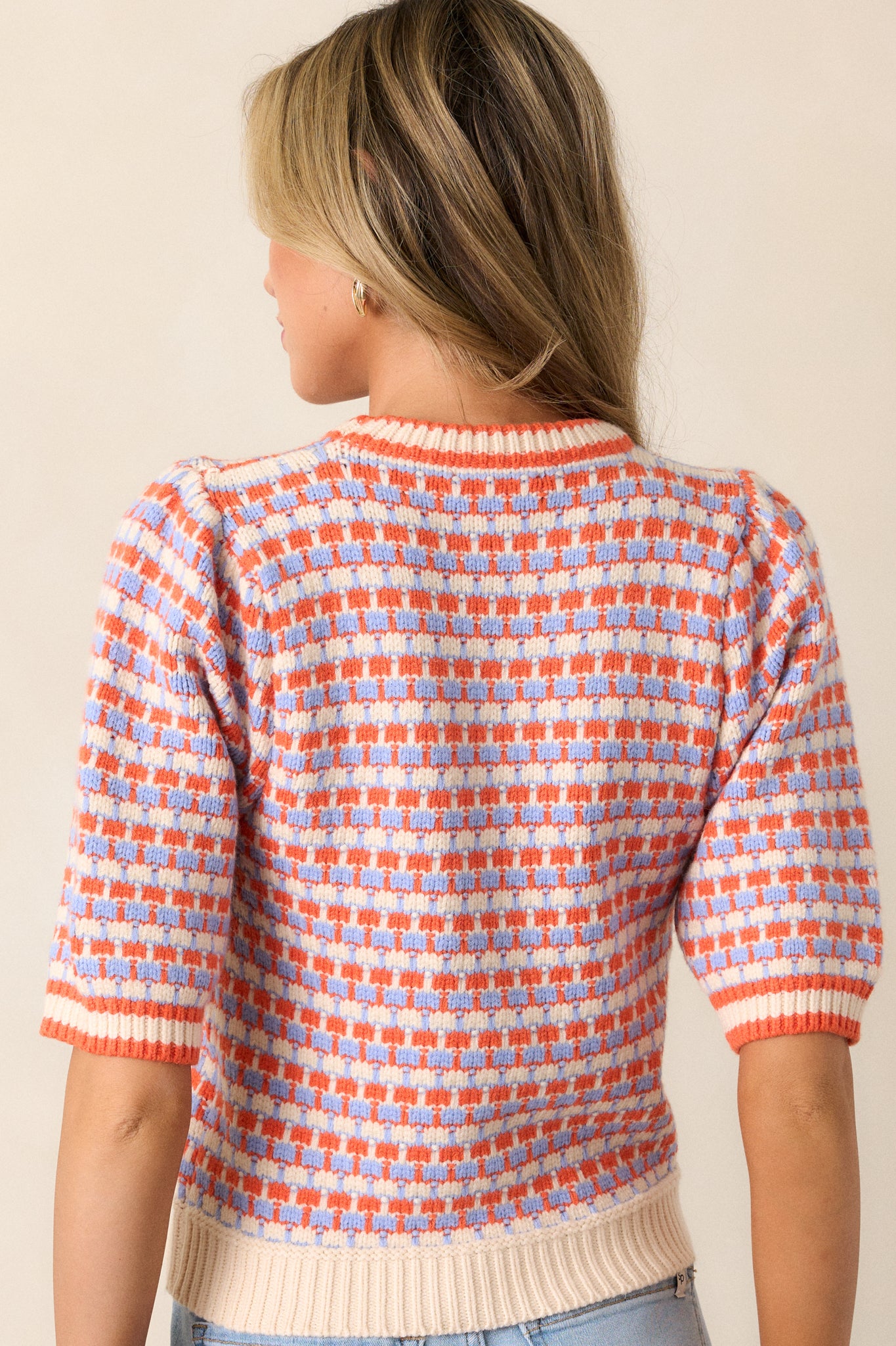 Back view of an ivory stripe sweater highlighting the multi-color stripe design, soft knit texture, and the ribbed hemline.