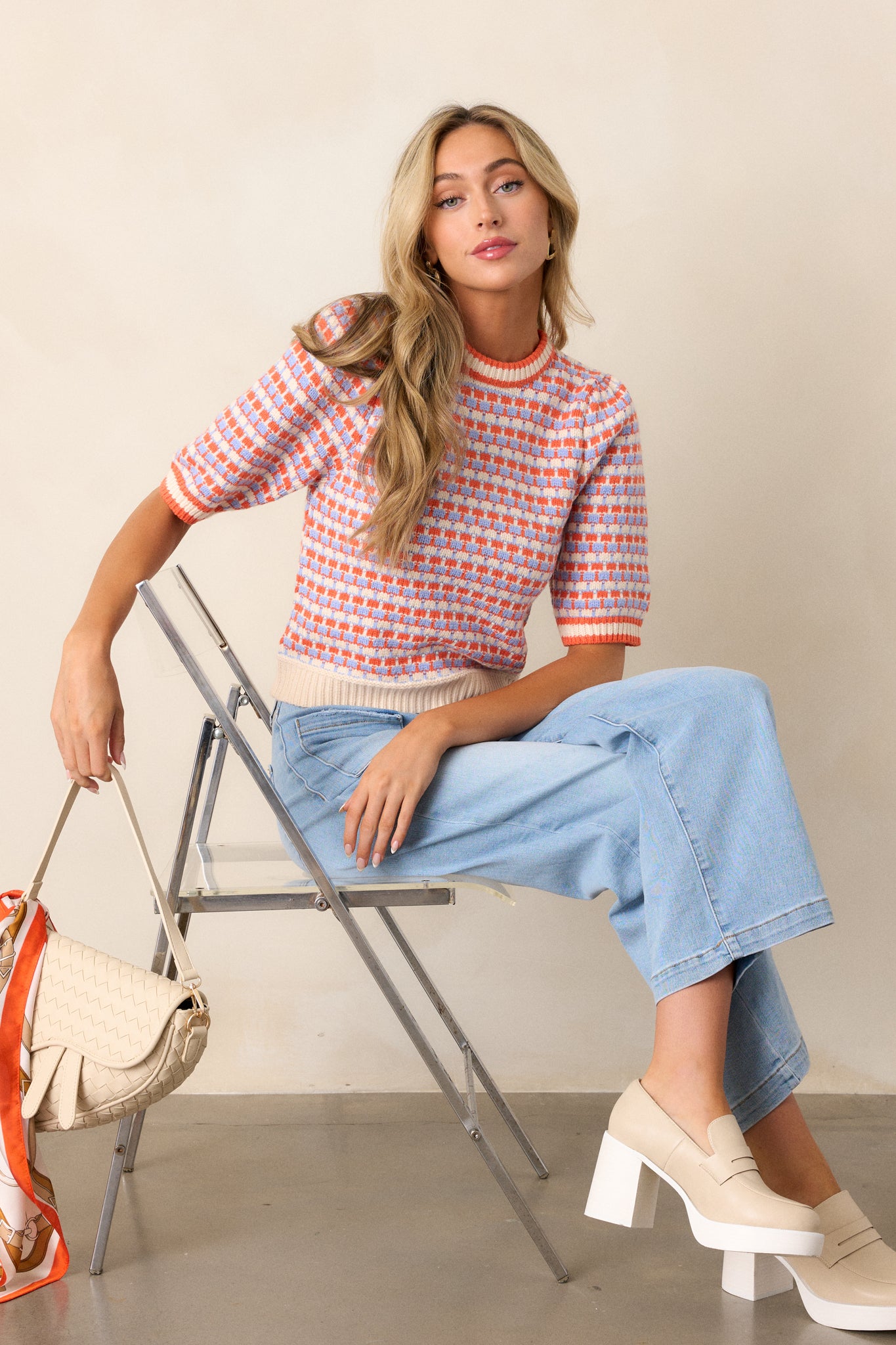 Front view of an ivory stripe sweater featuring a ribbed high neckline, a multi-color stripe design, a soft knit texture, a ribbed hemline, and short sleeves.