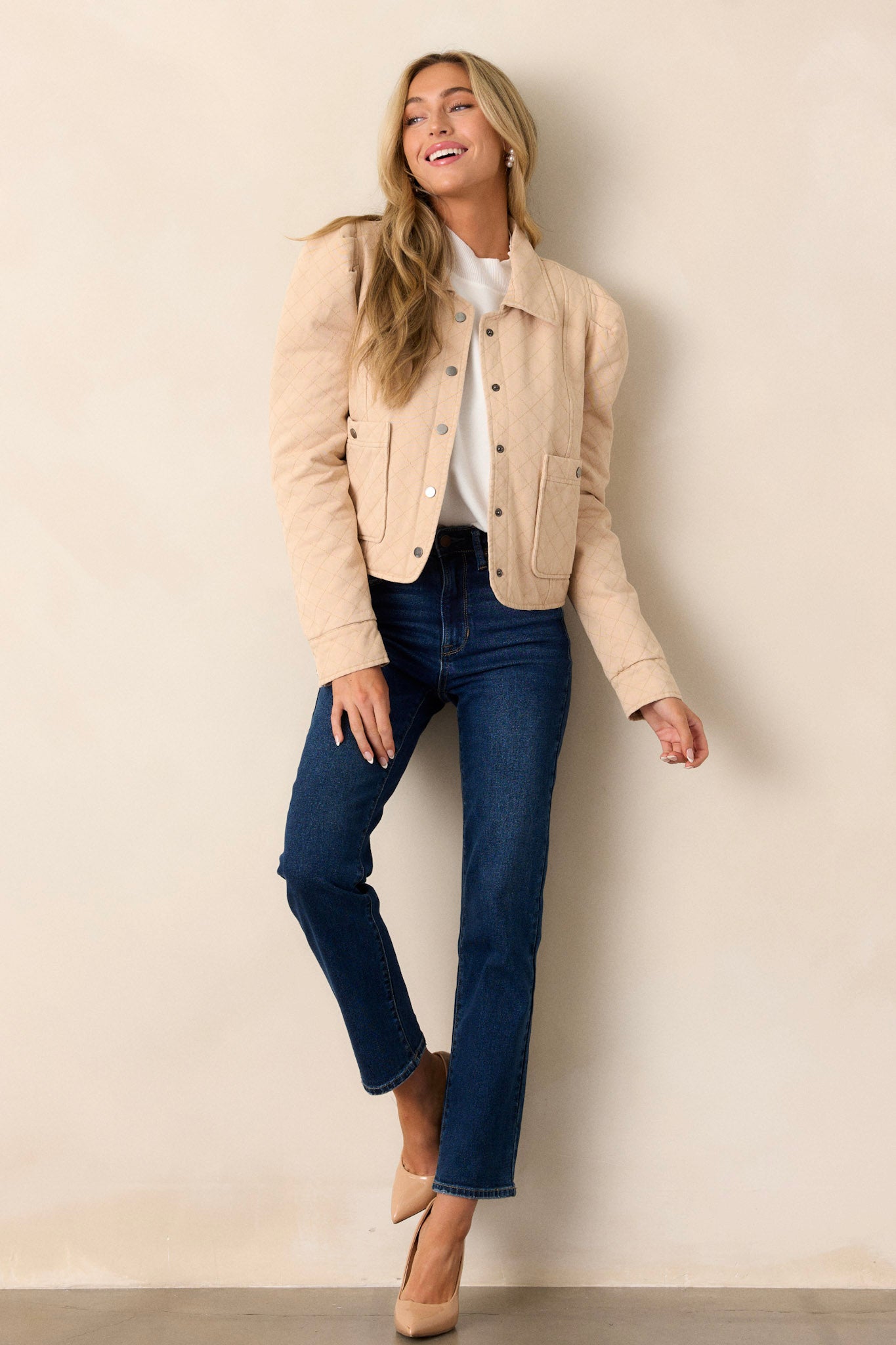 This taupe jacket features a collared neckline, a functional button front, puffed shoulders, and a slightly cropped hemline.