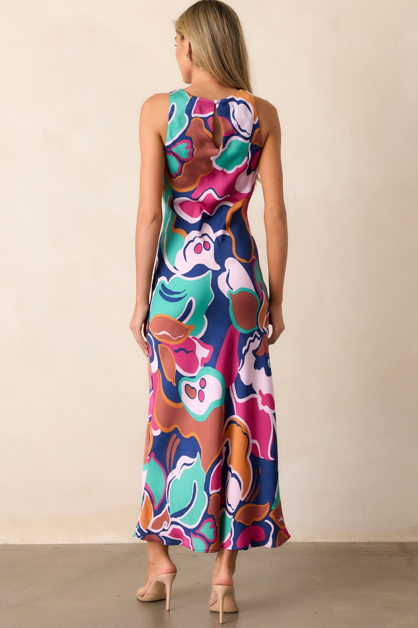 Back view of this midi dress that features a round neckline, a keyhole button closure, a unique abstract floral print, and a fun midi length.