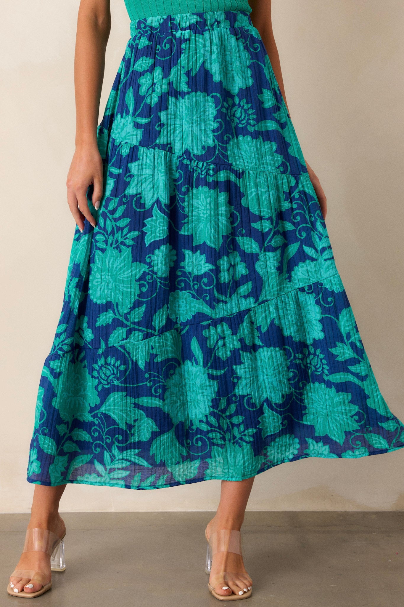 A cropped shot focusing on the lower tiers of the skirt, showcasing the asymmetrical layering and how the green floral pattern cascades down the fabric.