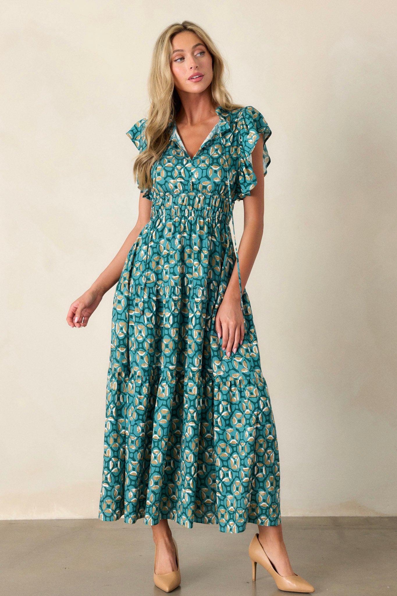 Full length view of a green maxi dress featuring a ruffled v-neckline, self-tie drawstring neckline, elastic waistbands, functional hip pockets, a tiered design, and short ruffle sleeves