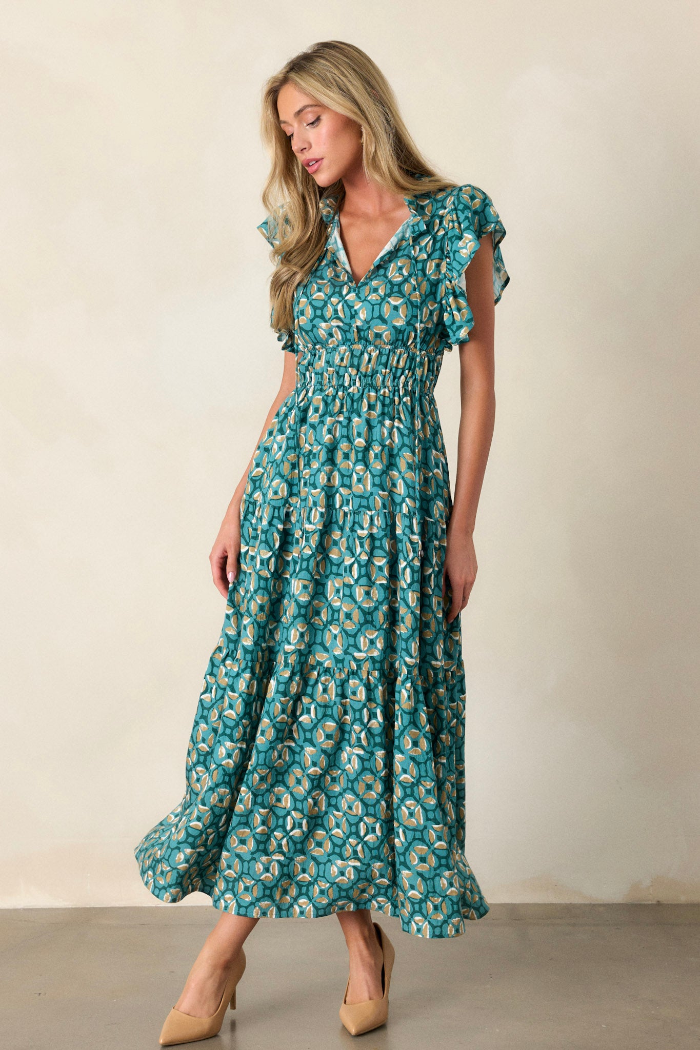 Action shot of a green maxi dress displaying the flow and movement of the fabric, highlighting the ruffled v-neckline, elastic waistbands, functional hip pockets, tiered design, and short ruffle sleeves